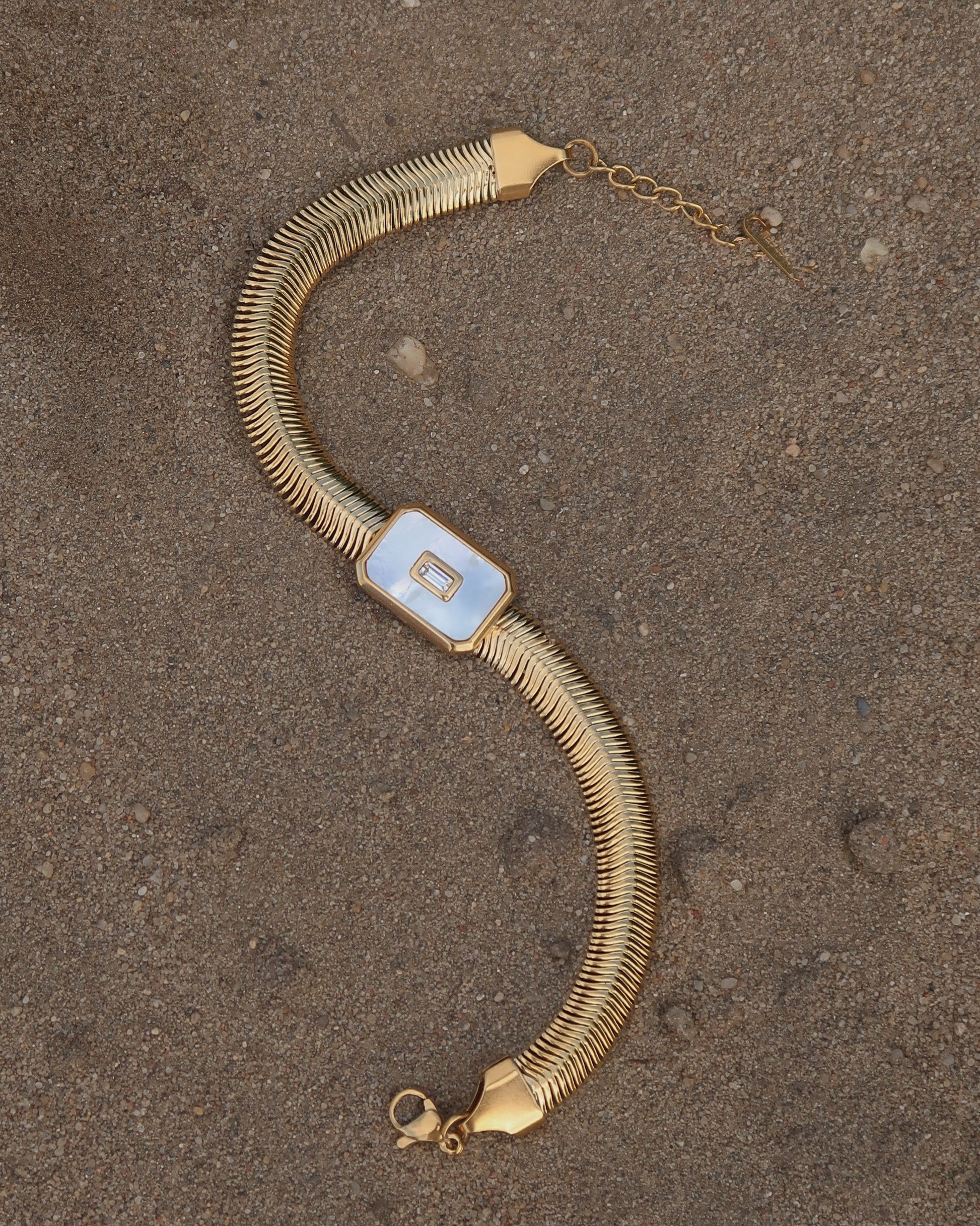 Dolly Bracelet met verfijnd slangenbandje, witte glanzende steen en verstelbare sluiting; waterproof en gemaakt van stainless steel.