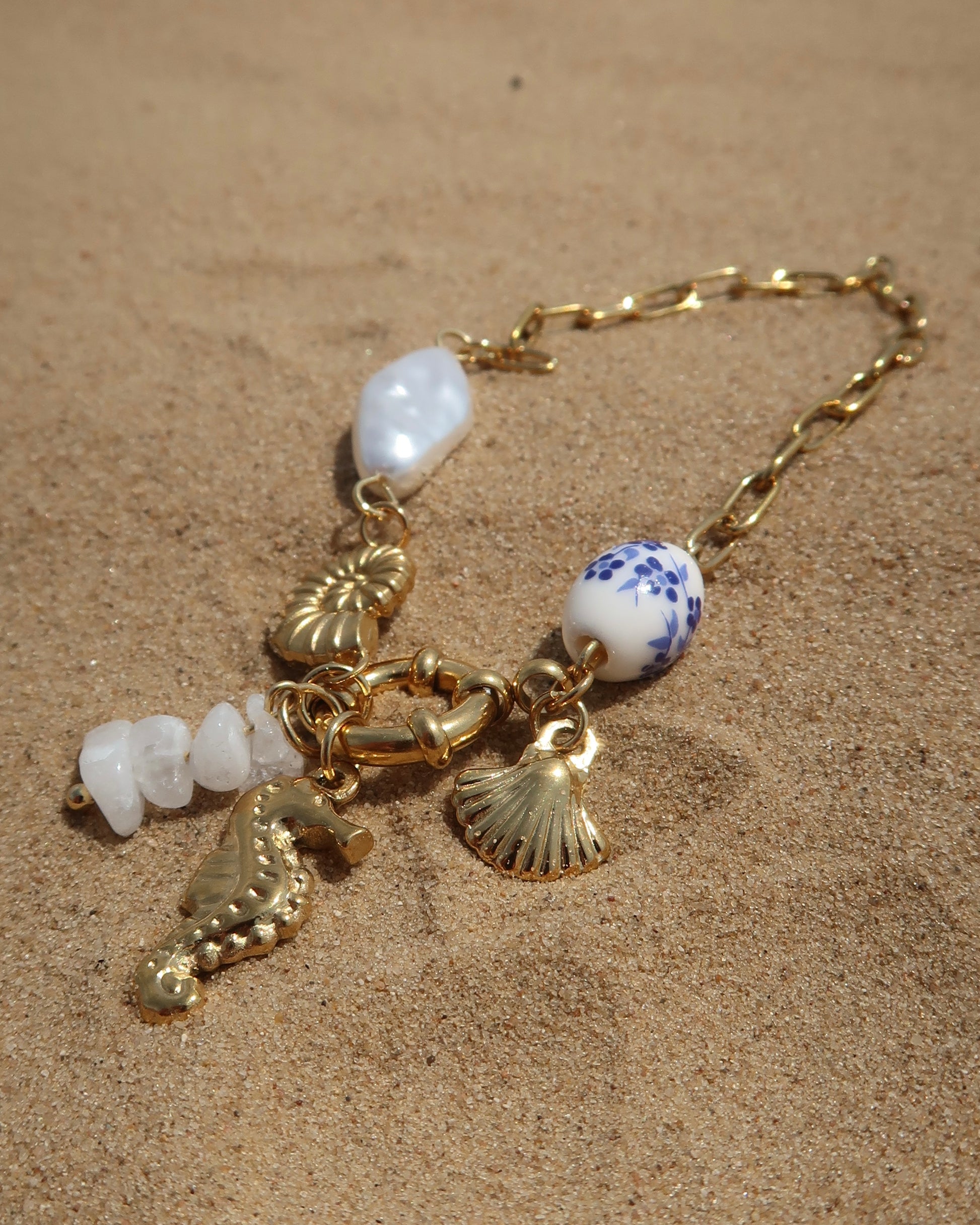 Goude bedelarmband van stainless steel met een zeepaard, schelpen en parels