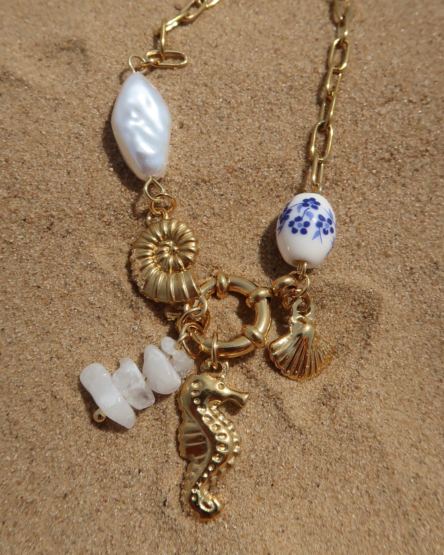 Goude bedelarmband van stainless steel met een zeepaard, schelpen en parels