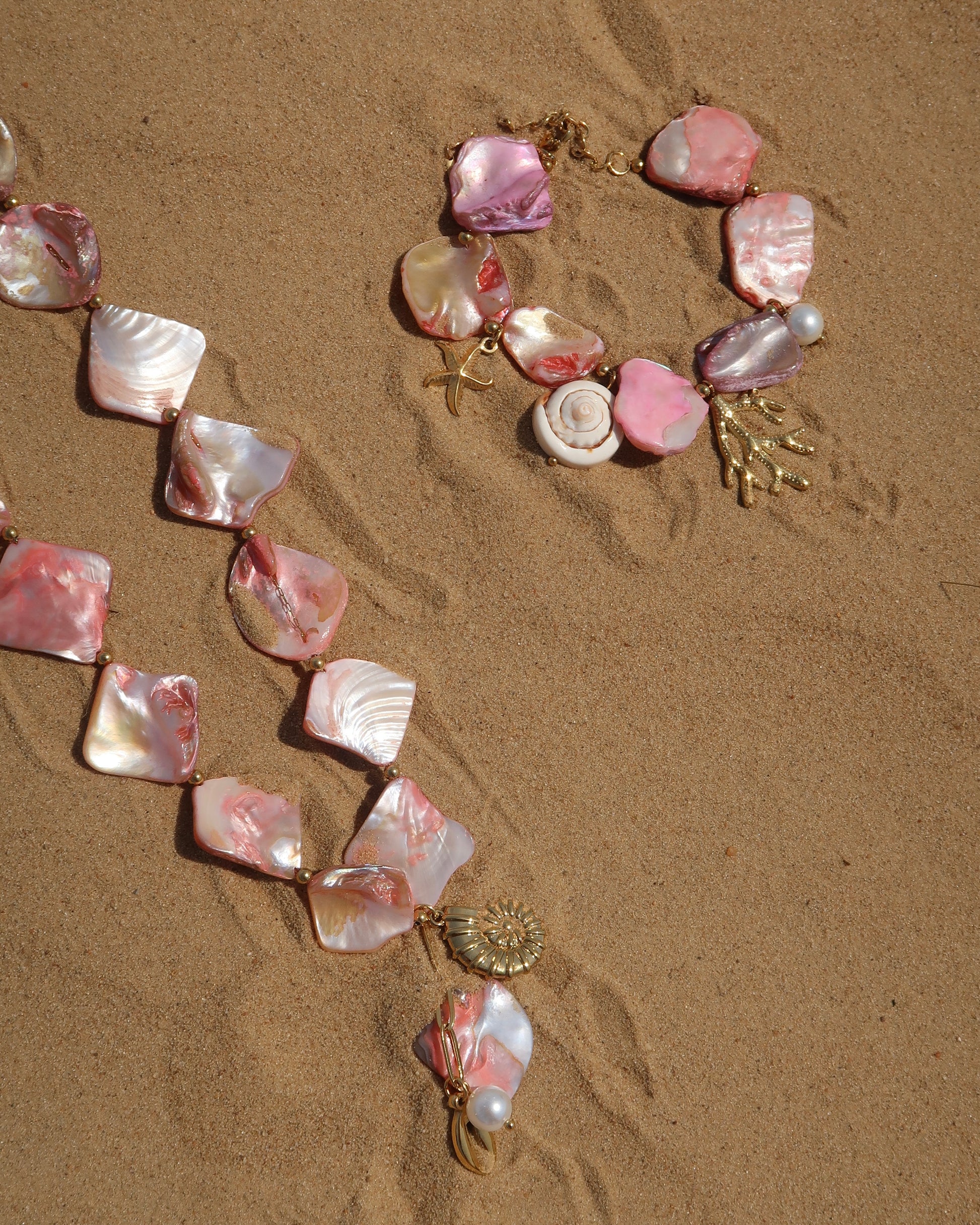 Zomerse sieradenset met roze schelpen en bedels, bestaande uit armband en ketting. Waterproof en van stainless steel.