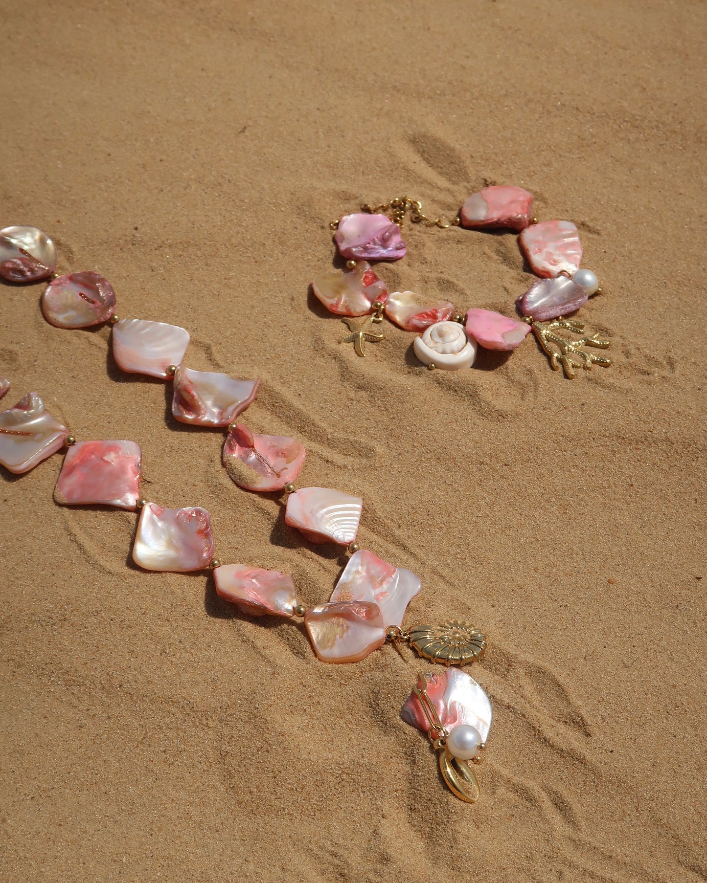Zomerse sieradenset met roze schelpen en bedels, bestaande uit armband en ketting. Waterproof en van stainless steel.