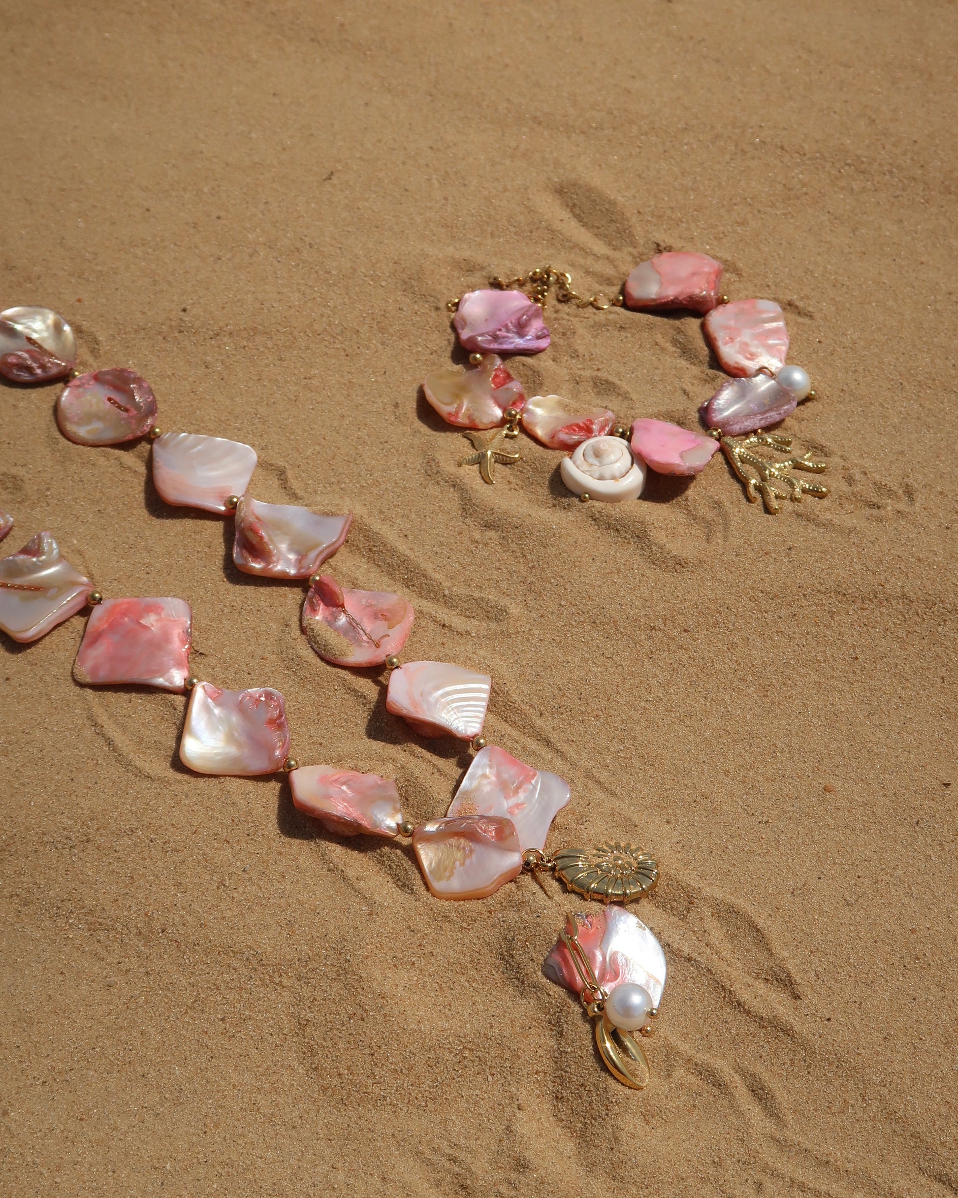 Zomerse sieradenset met roze schelpen en bedels, bestaande uit armband en ketting. Waterproof en van stainless steel.