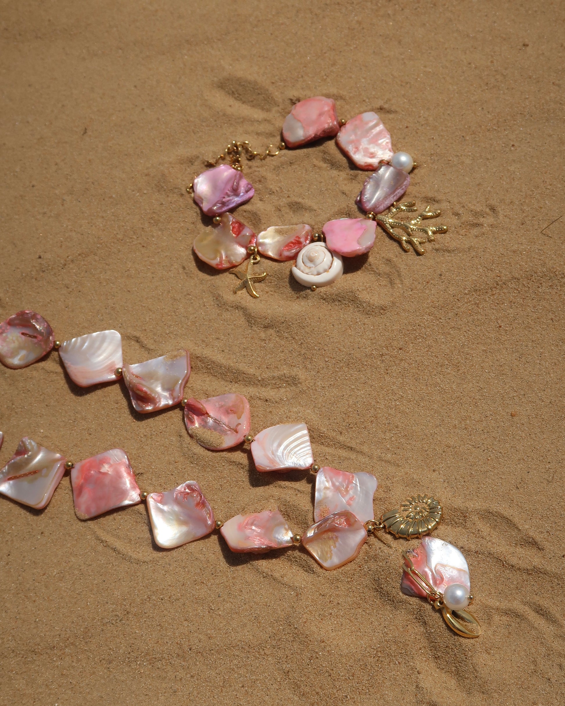 Zomerse sieradenset met roze schelpen en bedels, bestaande uit armband en ketting. Waterproof en van stainless steel.