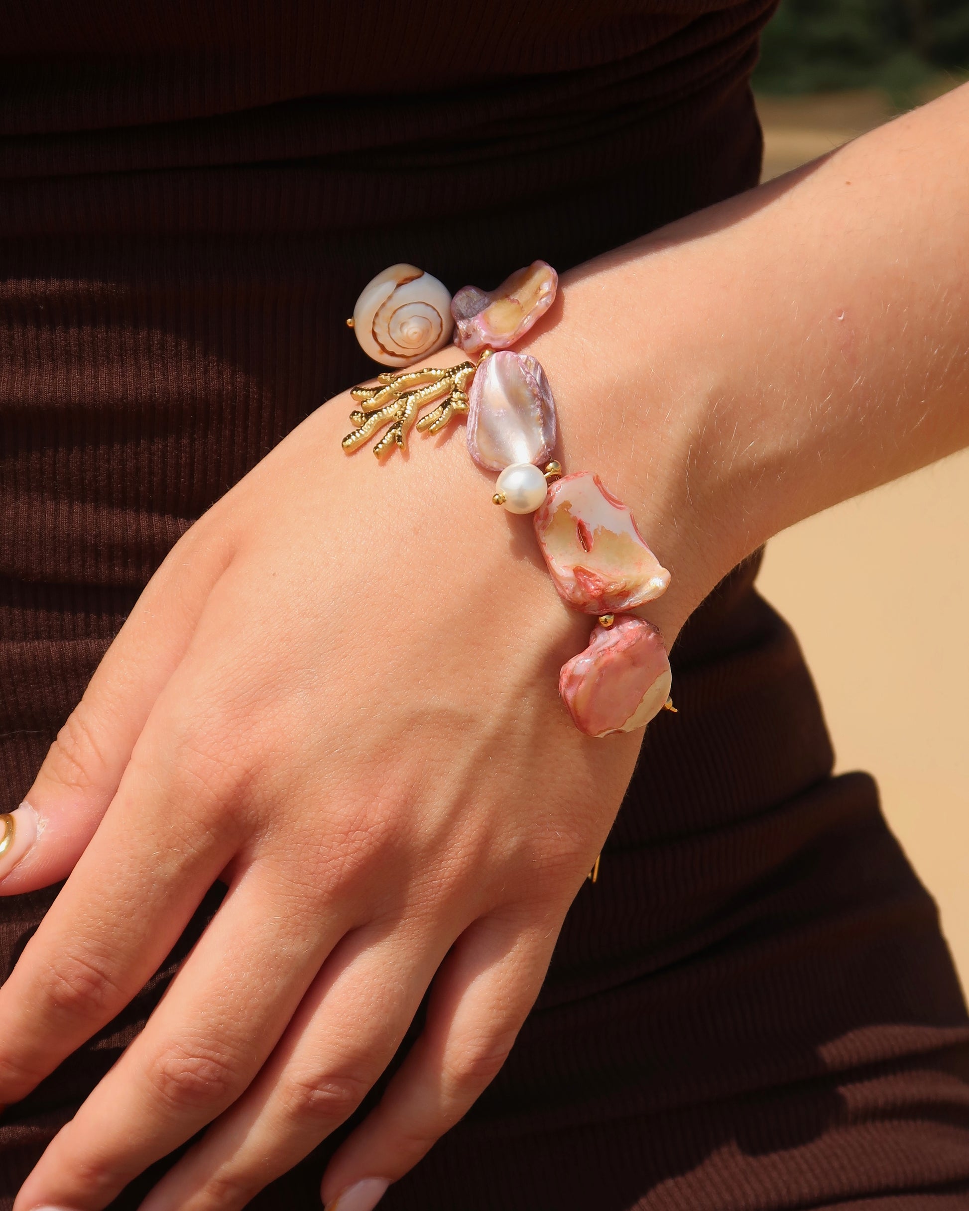 Statement armband van roze schelpen met speelse bedels