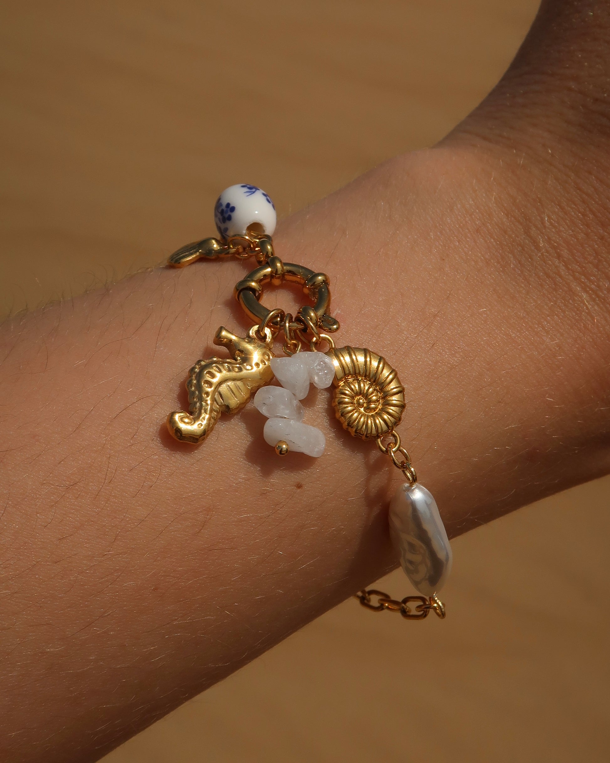 Goude bedelarmband van stainless steel met een zeepaard, schelpen en parels