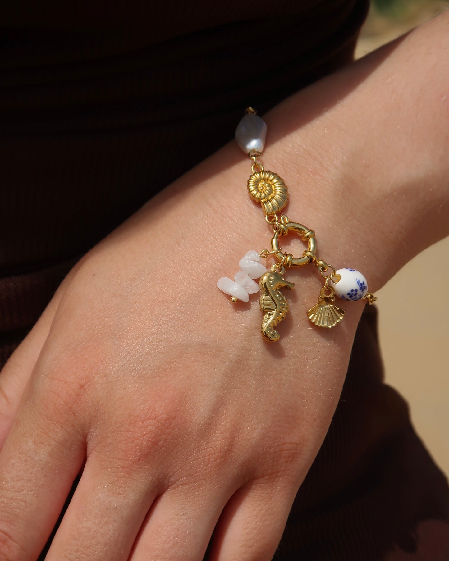 Goude bedelarmband van stainless steel met een zeepaard, schelpen en parels