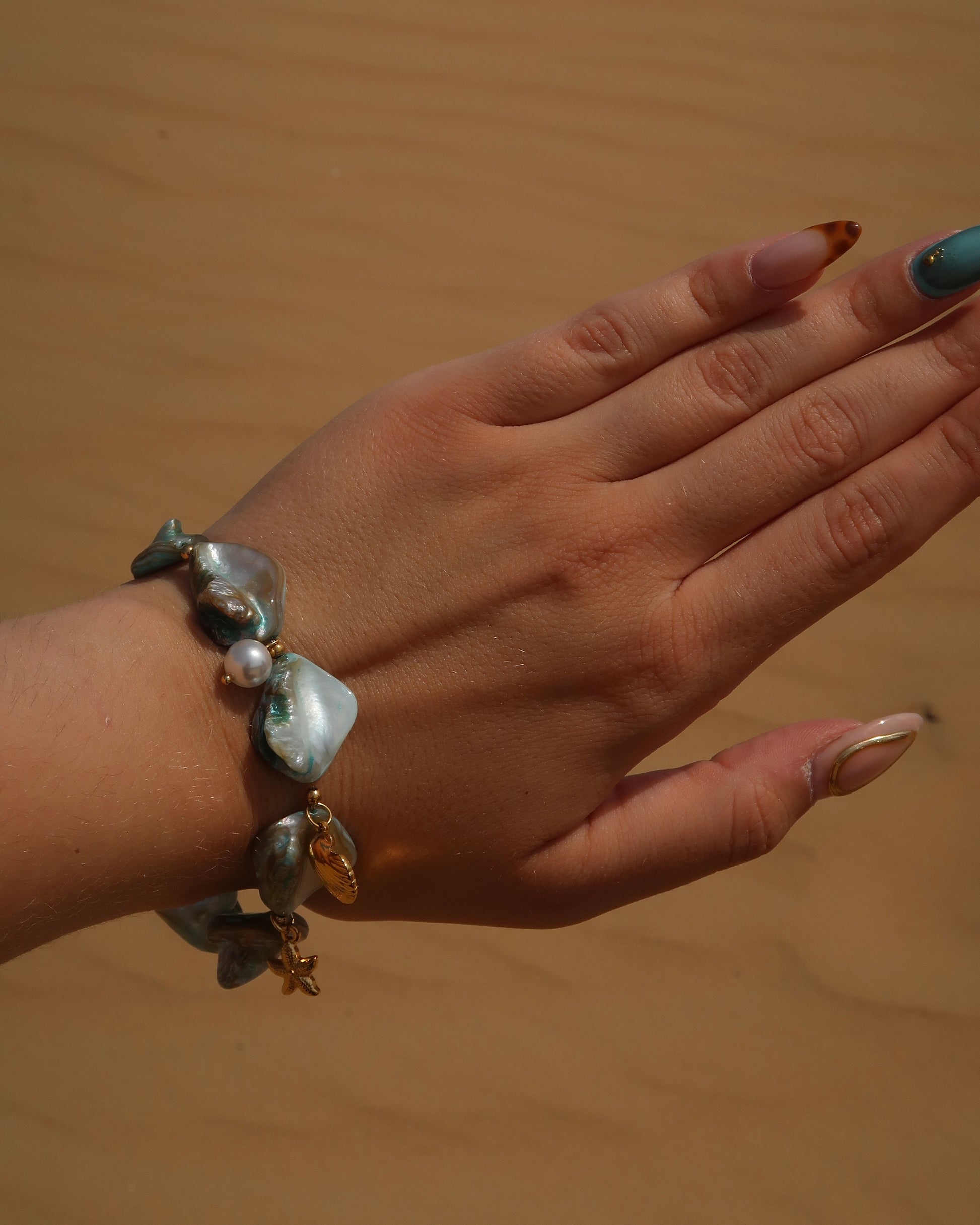 Statement armband van blauwe schelpen met speelse bedels