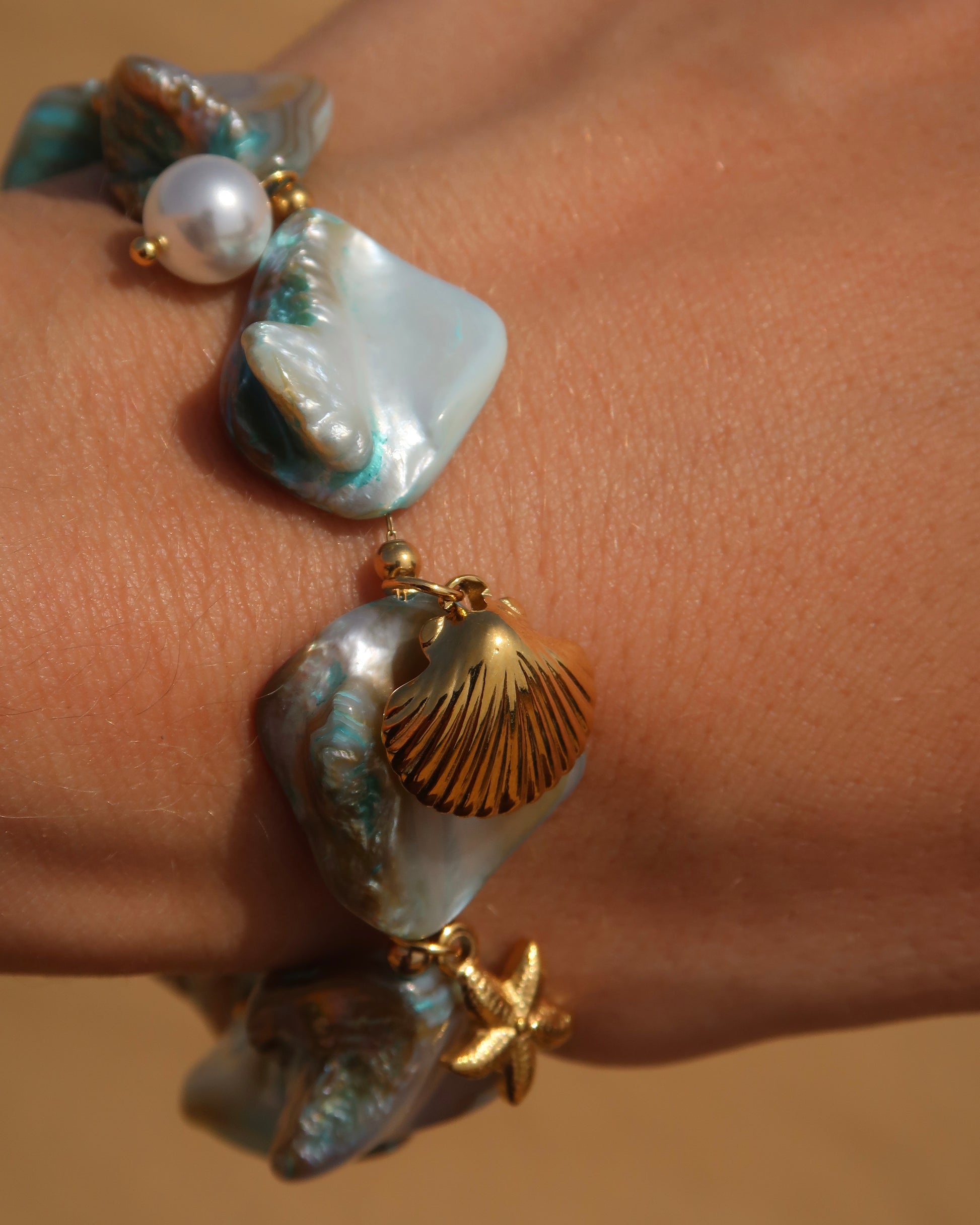 Statement armband van blauwe schelpen met speelse bedels