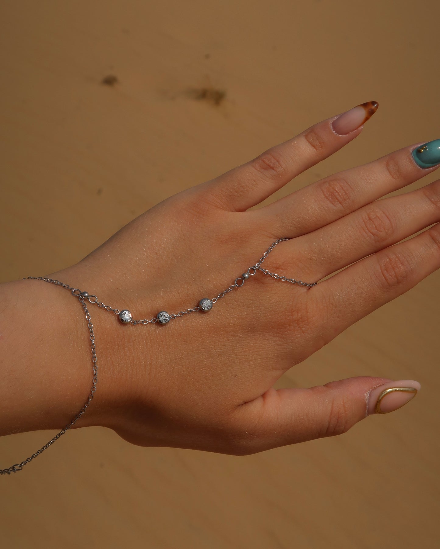 Lume Hand Chain armband voor hand en pols, verkrijgbaar in goud en zilver, stainless steel, waterproof, met drie subtiele steentjes, verstelbaar en ook verkrijgbaar als sieradenset met bijpassende ketting.