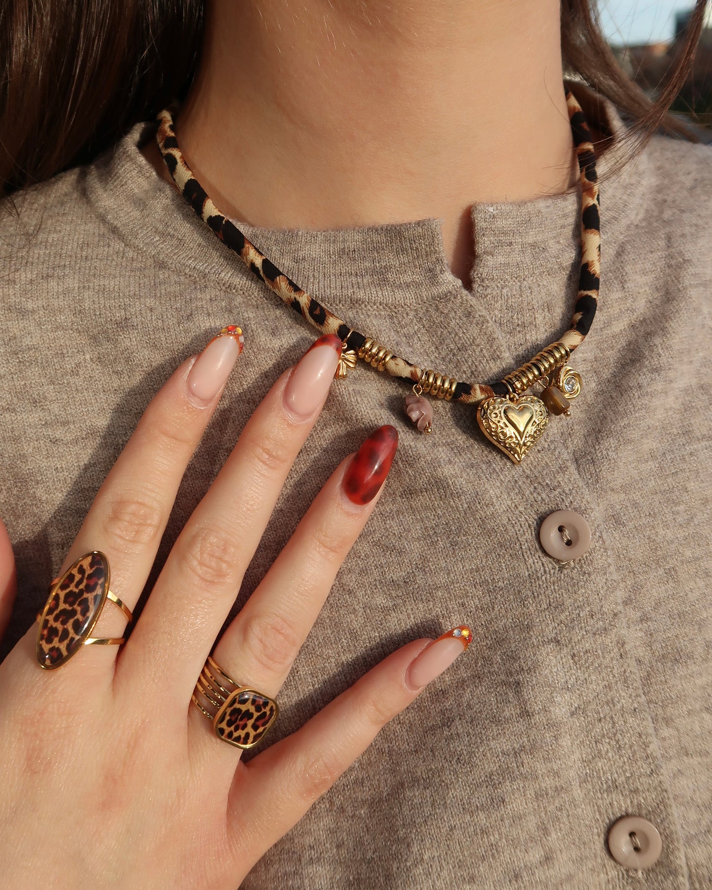 Gouden elastische panterprintketting met kleine hangertjes en verfijnde gouden details.