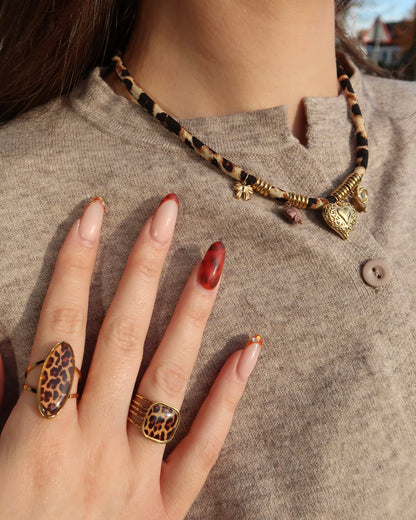 Gouden elastische panterprintketting met kleine hangertjes en verfijnde gouden details.