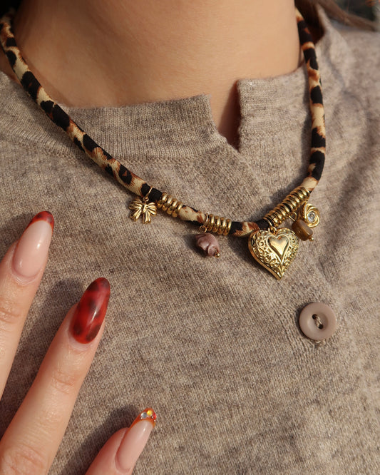 Gouden elastische panterprintketting met kleine hangertjes en verfijnde gouden details.