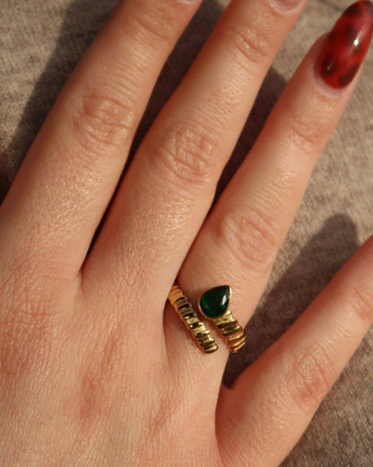 Gouden spiraalvormige ring met reliëf en groene druppelvormige steen aan het uiteinde, gemaakt van stainless steel