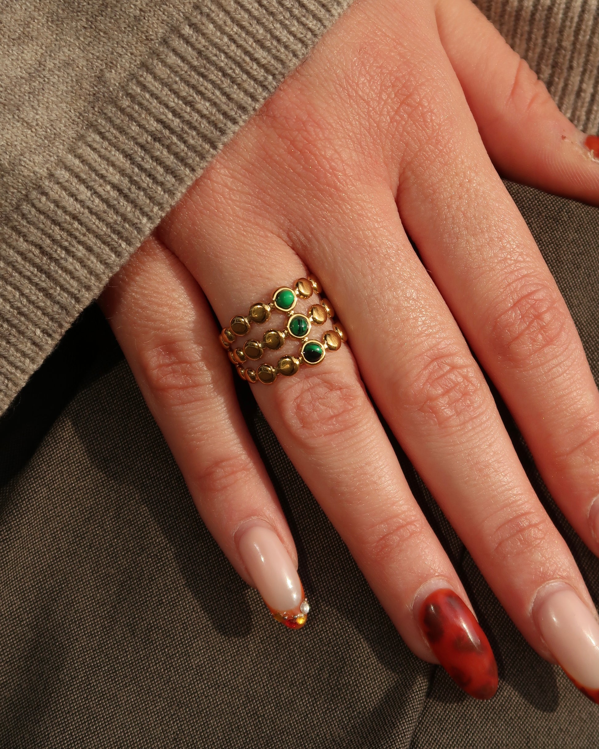 Gouden verstelbare stainless steel ring met drie groene steentjes en verfijnde details, uitgevoerd in een gelaagd design