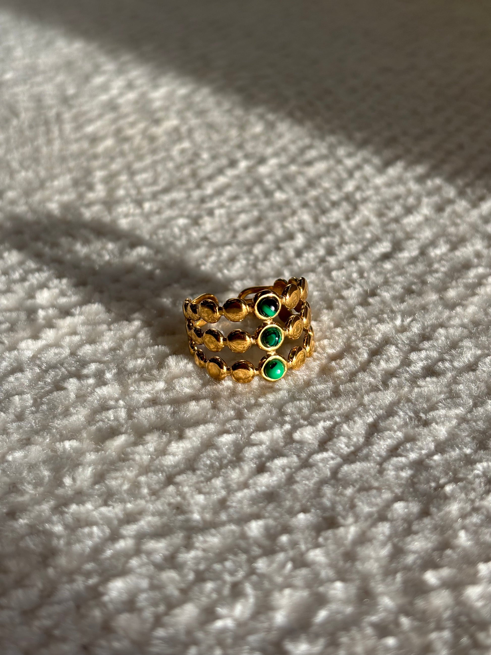 Gouden verstelbare stainless steel ring met drie groene steentjes en verfijnde details, uitgevoerd in een gelaagd design