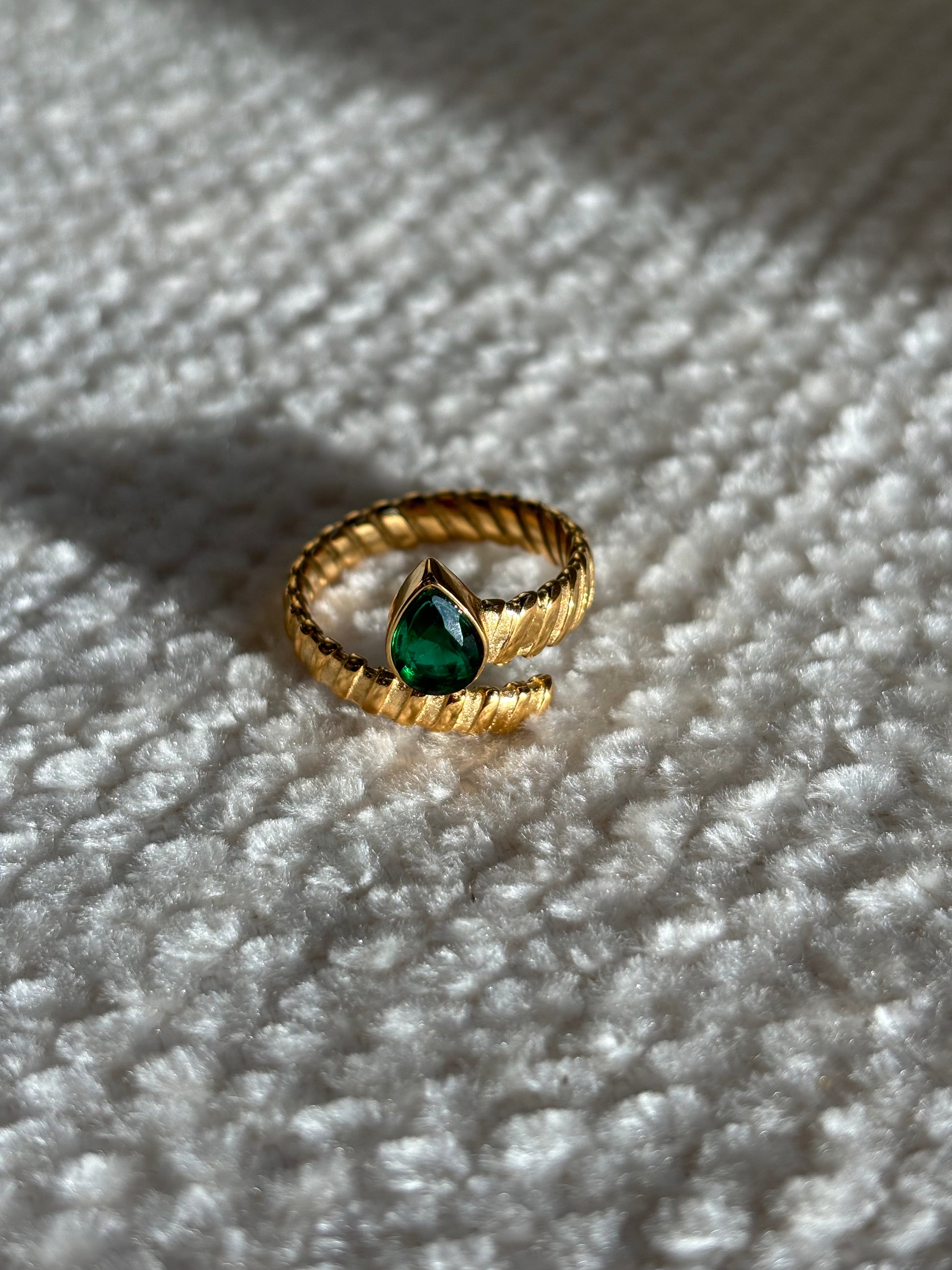 Gouden spiraalvormige ring met reliëf en groene druppelvormige steen aan het uiteinde, gemaakt van stainless steel