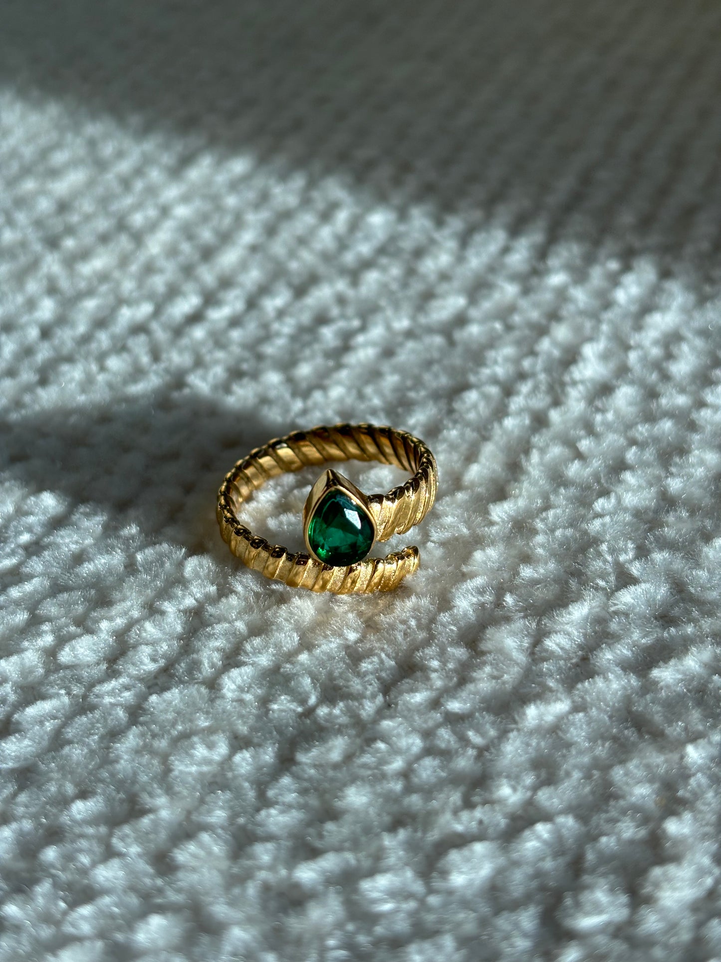 Gouden spiraalvormige ring met reliëf en groene druppelvormige steen aan het uiteinde, gemaakt van stainless steel