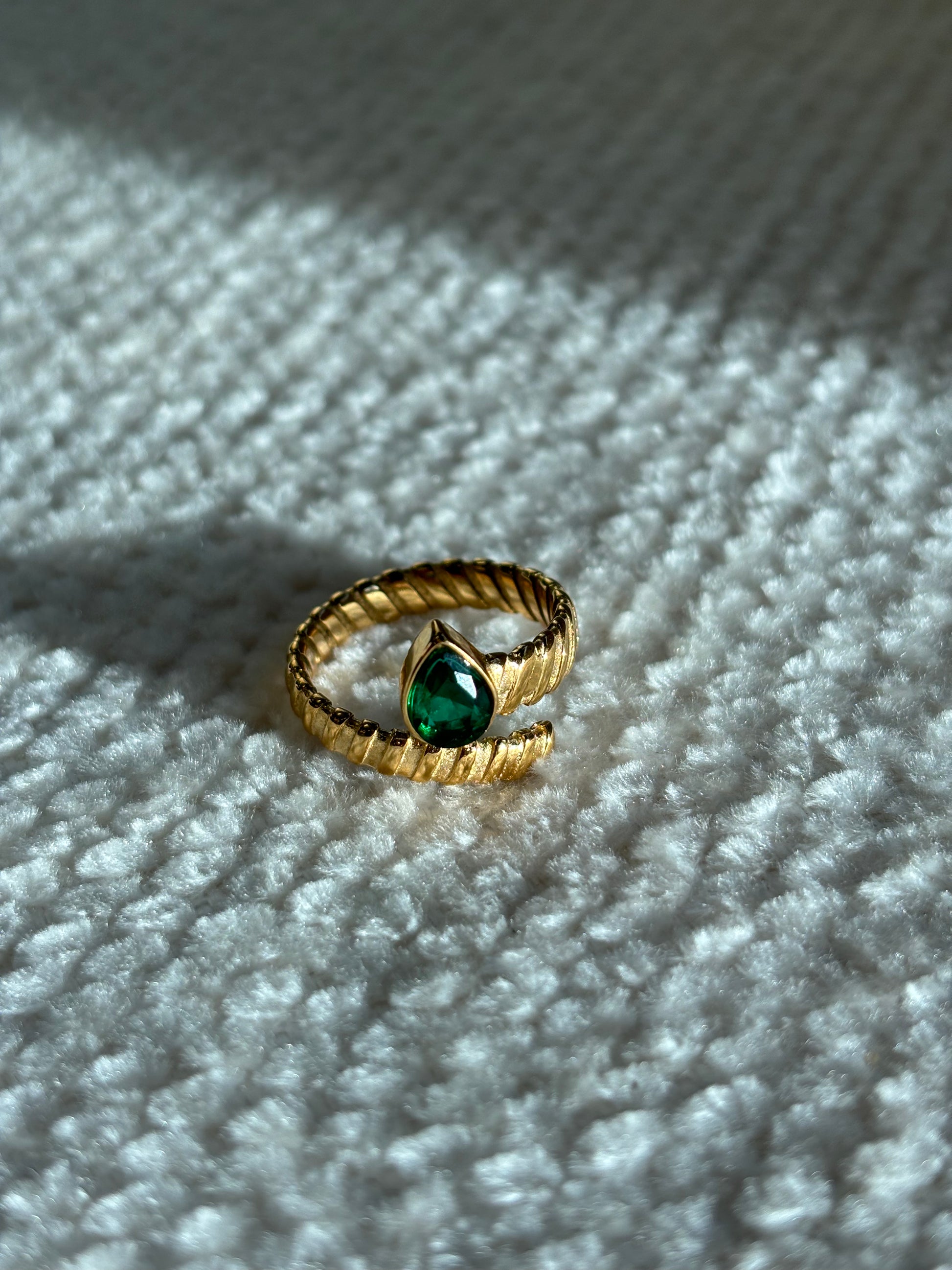 Gouden spiraalvormige ring met reliëf en groene druppelvormige steen aan het uiteinde, gemaakt van stainless steel