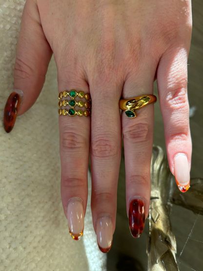 Gouden verstelbare stainless steel ring met drie groene steentjes en verfijnde details, uitgevoerd in een gelaagd design