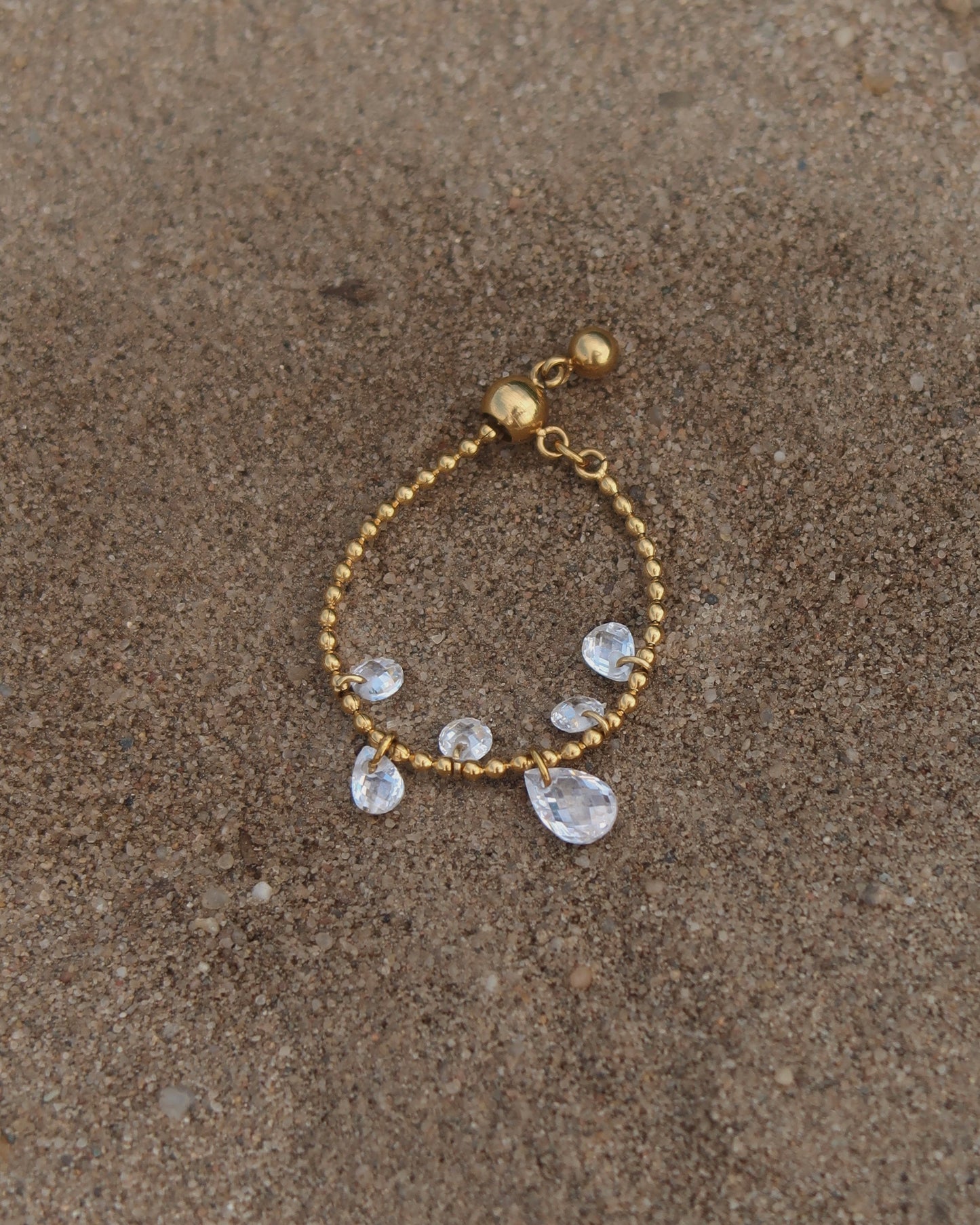 Verstelbare stainless steel ring met bolletjesbandje en hangende druppelvormige steentjes, verkrijgbaar in goud en zilver