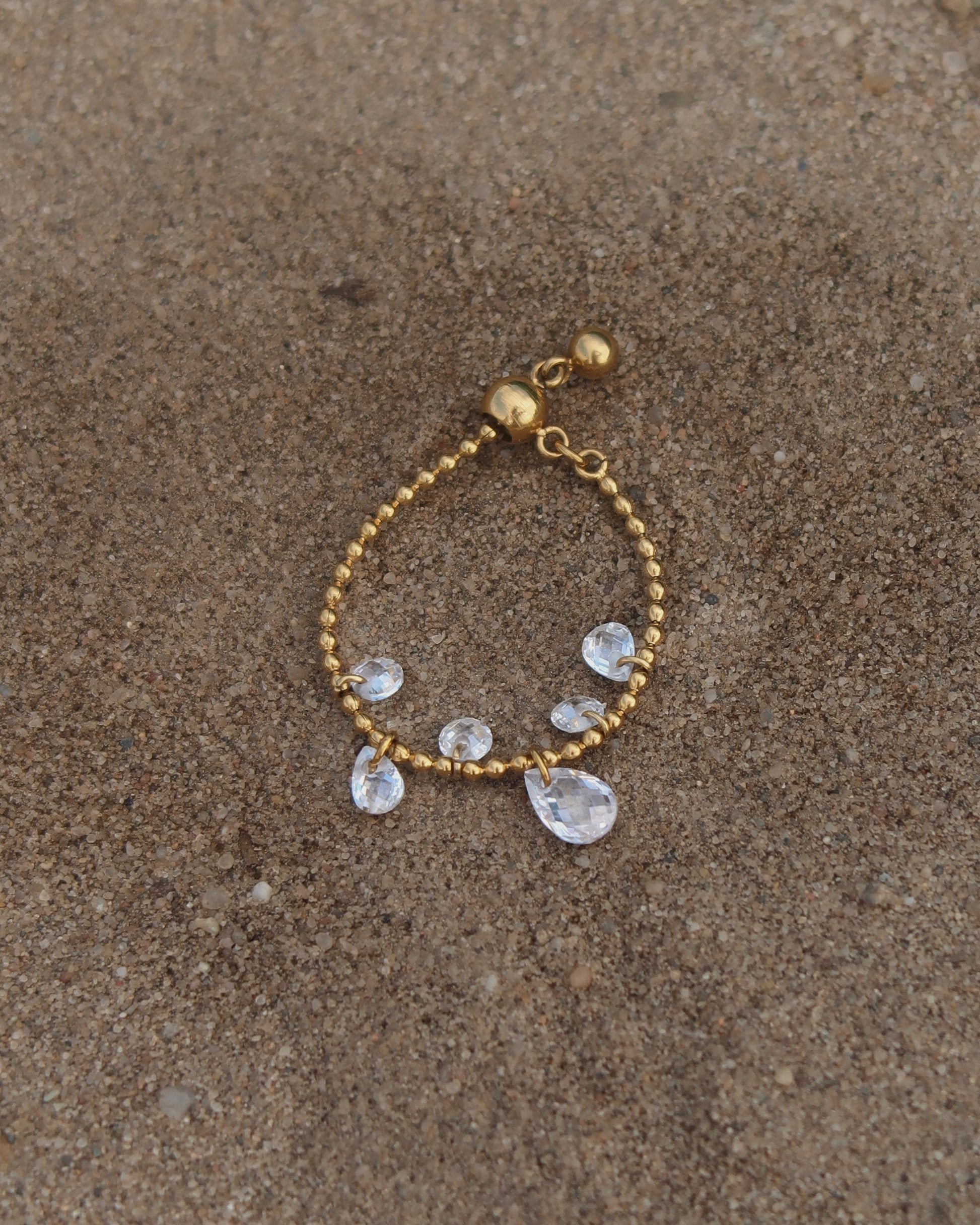 Verstelbare stainless steel ring met bolletjesbandje en hangende druppelvormige steentjes, verkrijgbaar in goud en zilver