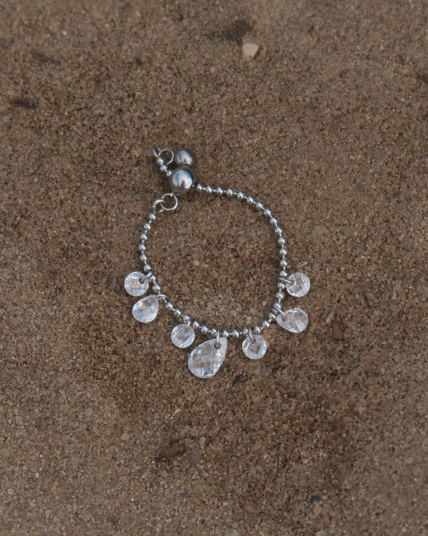 Verstelbare stainless steel ring met bolletjesbandje en hangende druppelvormige steentjes, verkrijgbaar in goud en zilver