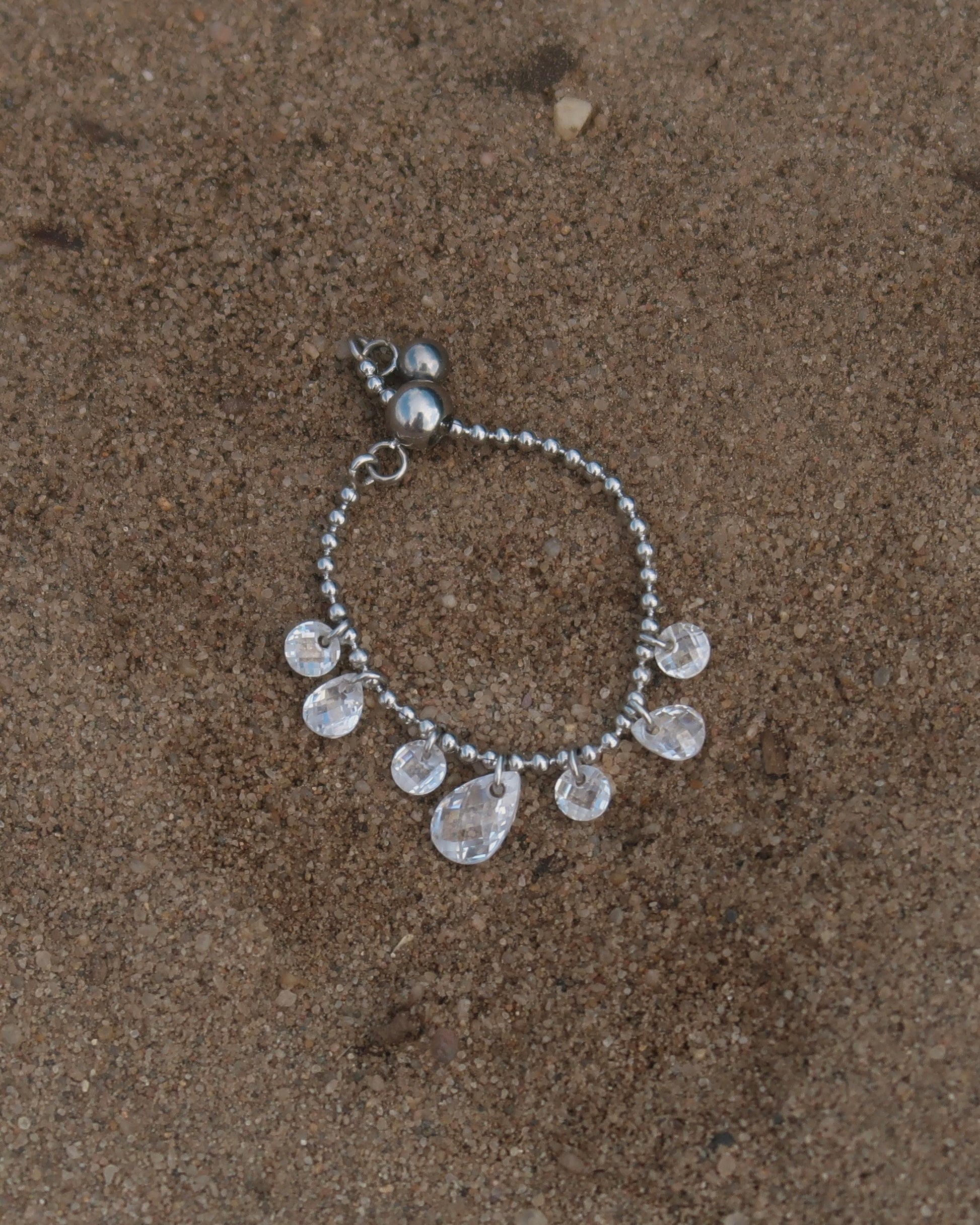 Verstelbare stainless steel ring met bolletjesbandje en hangende druppelvormige steentjes, verkrijgbaar in goud en zilver