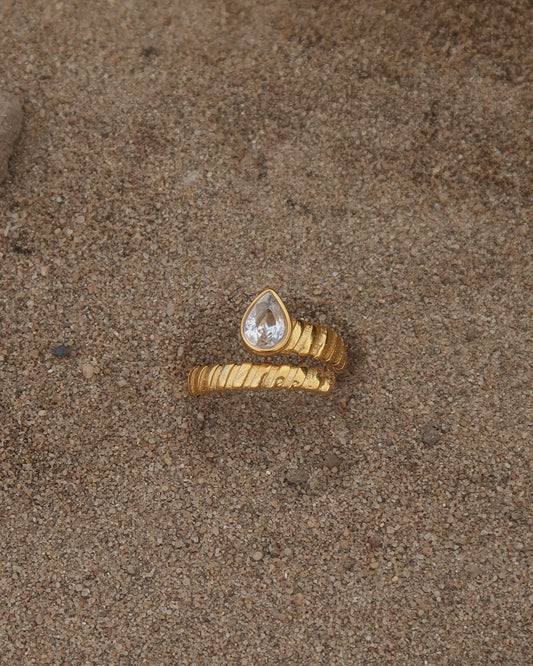 Gouden spiraalvormige ring met reliëf en zilverkleurige druppelvormige steen aan het uiteinde, gemaakt van stainless steel