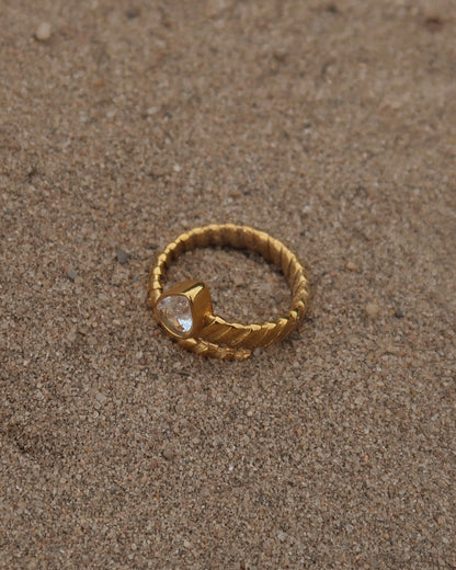 Gouden spiraalvormige ring met reliëf en zilverkleurige druppelvormige steen aan het uiteinde, gemaakt van stainless steel