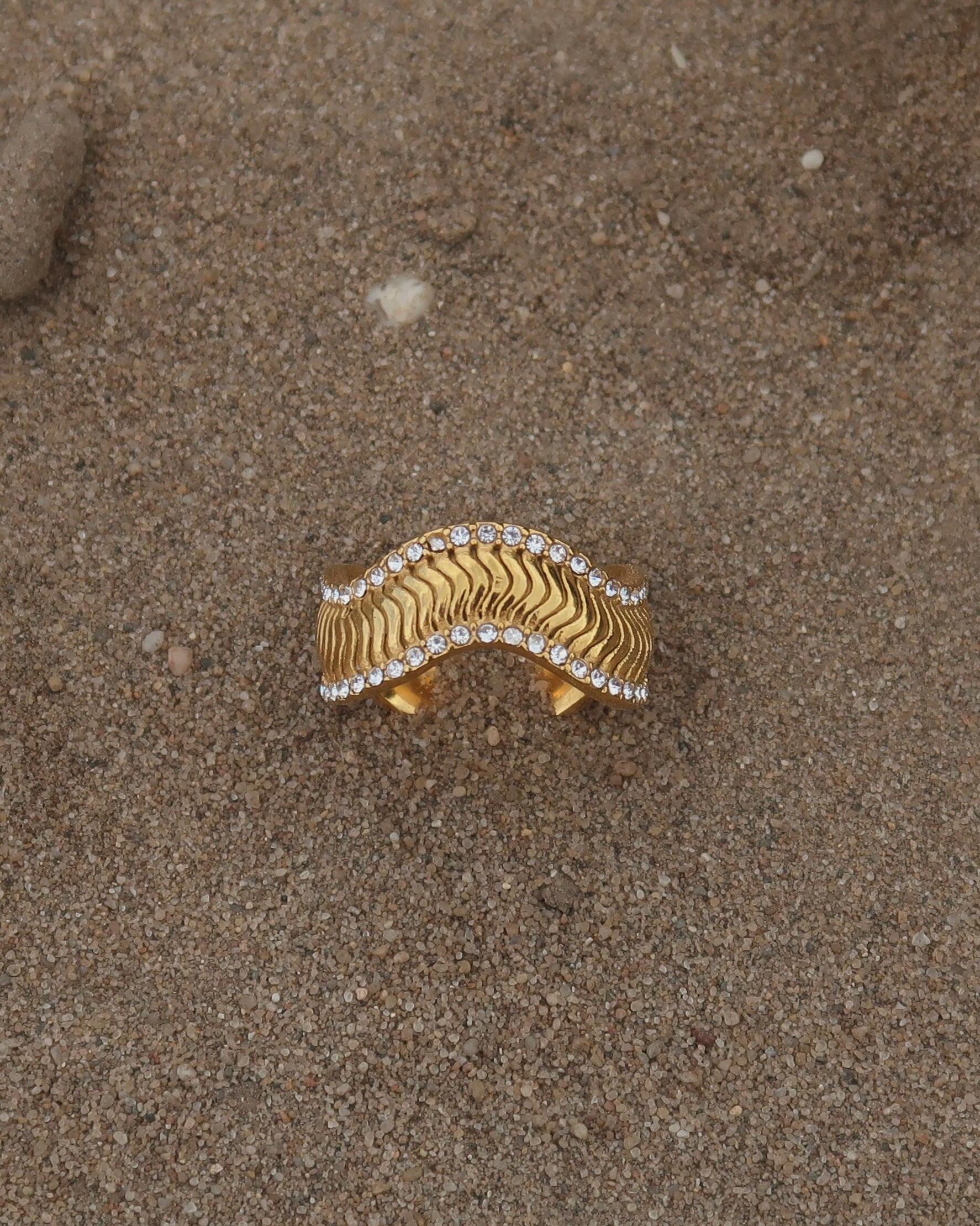 Gouden ring met golvend reliëf en zilverkleurige steentjes langs de randen - gemaakt van stainless steel
