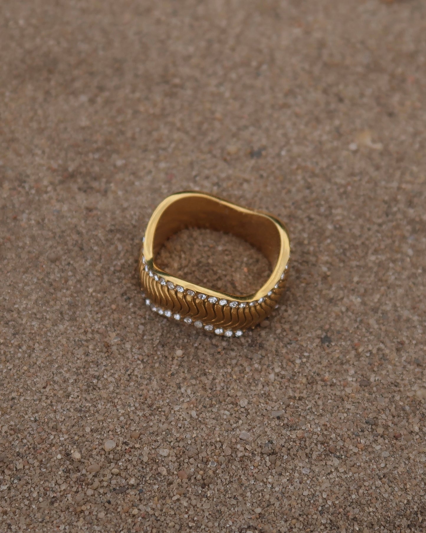 Gouden ring met golvend reliëf en zilverkleurige steentjes langs de randen - gemaakt van stainless steel