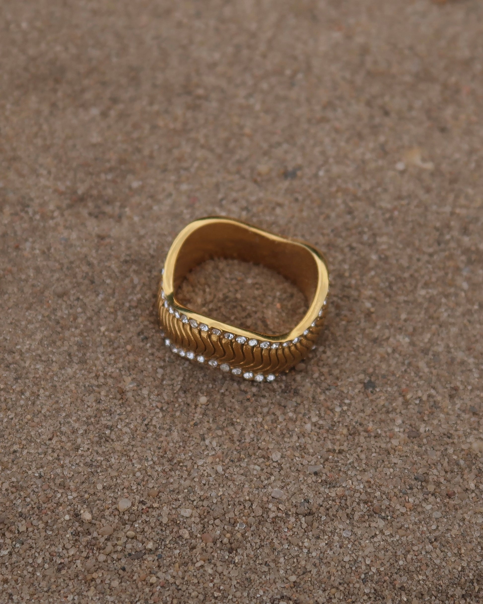 Gouden ring met golvend reliëf en zilverkleurige steentjes langs de randen - gemaakt van stainless steel