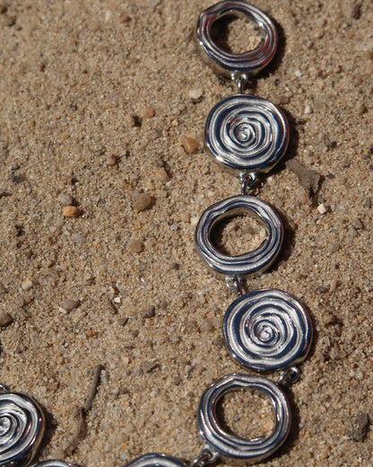 Zilveren statementketting met aaneengeschakelde ronde schelpvormen in verschillende stijlen.