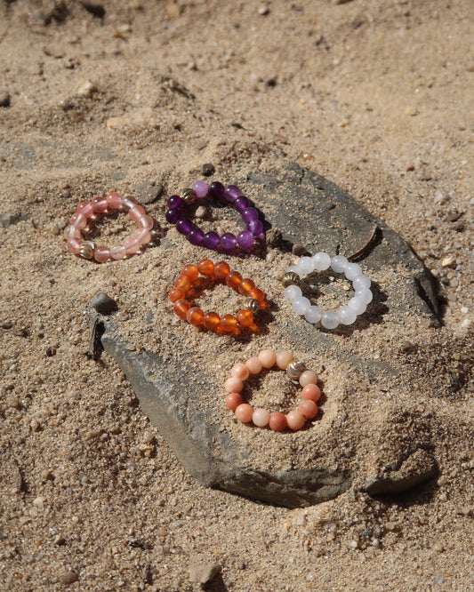 Kleurrijke elastische ring met kleine bolletjes en een centraal goudkleurig bolletje, perfect om te combineren met andere ringen