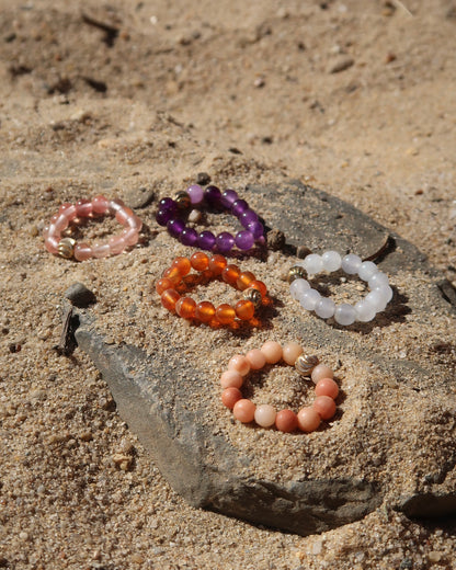 Kleurrijke elastische ring met kleine bolletjes en een centraal goudkleurig bolletje, perfect om te combineren met andere ringen