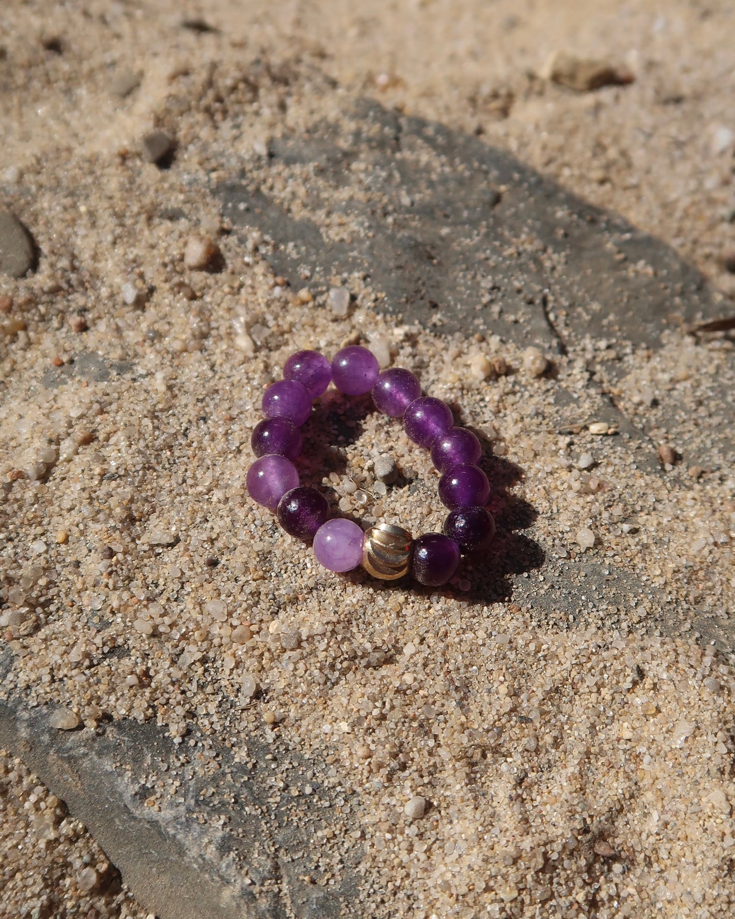 Paarse elastische ring met kleine bolletjes en een centraal goudkleurig bolletje, perfect om te combineren met andere ringen