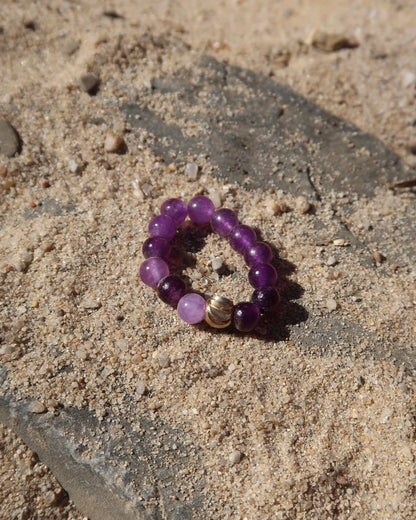 Paarse elastische ring met kleine bolletjes en een centraal goudkleurig bolletje, perfect om te combineren met andere ringen