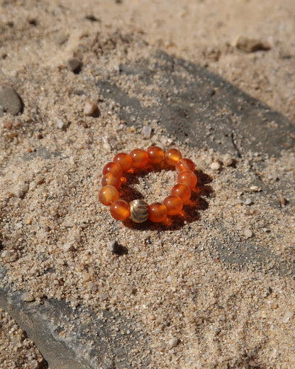 Oranje elastische ring met kleine bolletjes en een centraal goudkleurig bolletje, perfect om te combineren met andere ringen