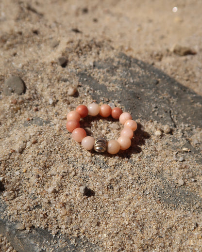 Zalm elastische ring met kleine bolletjes en een centraal goudkleurig bolletje, perfect om te combineren met andere ringen