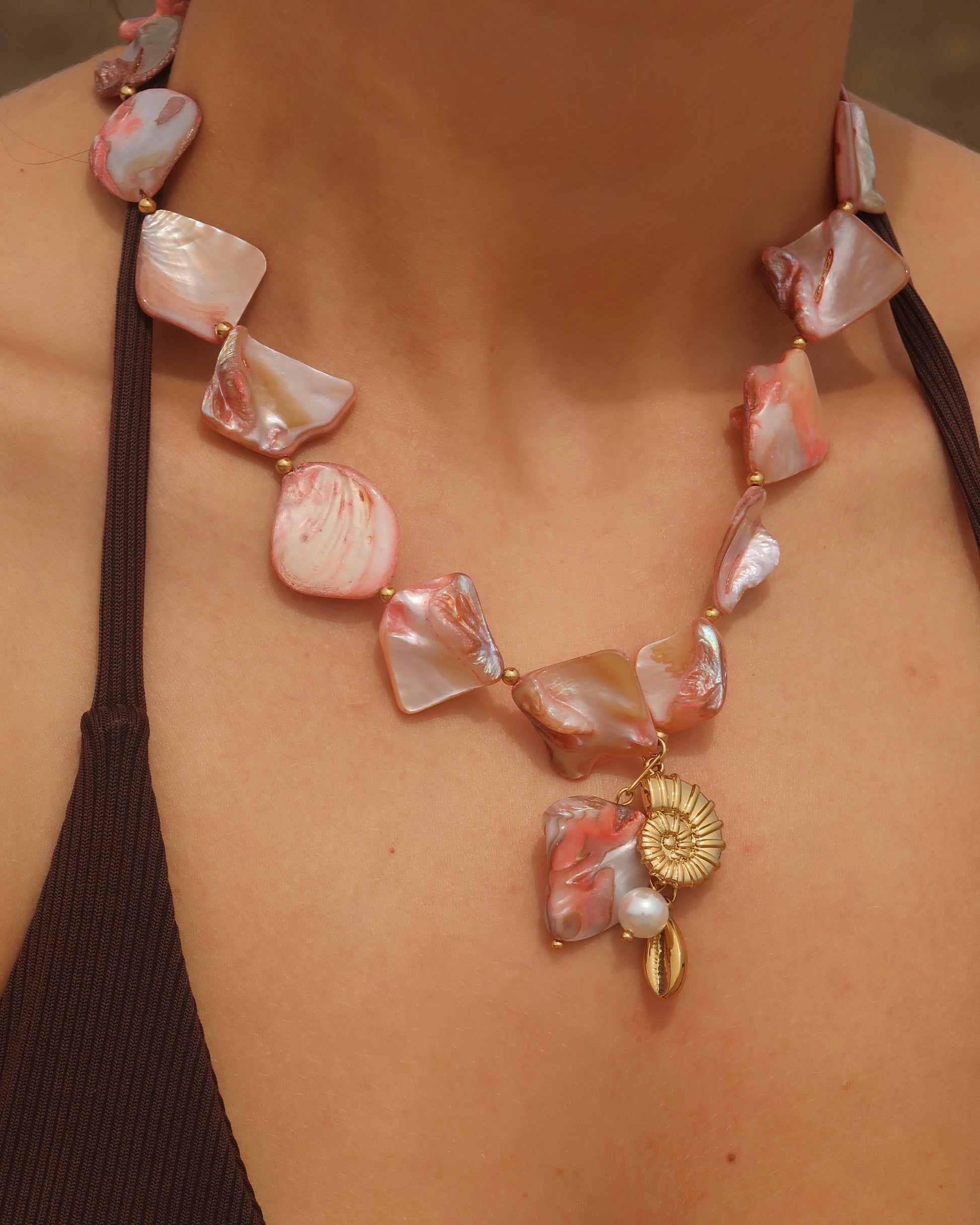 Statement ketting van roze schelpen met gouden hangers, waaronder schelpen
