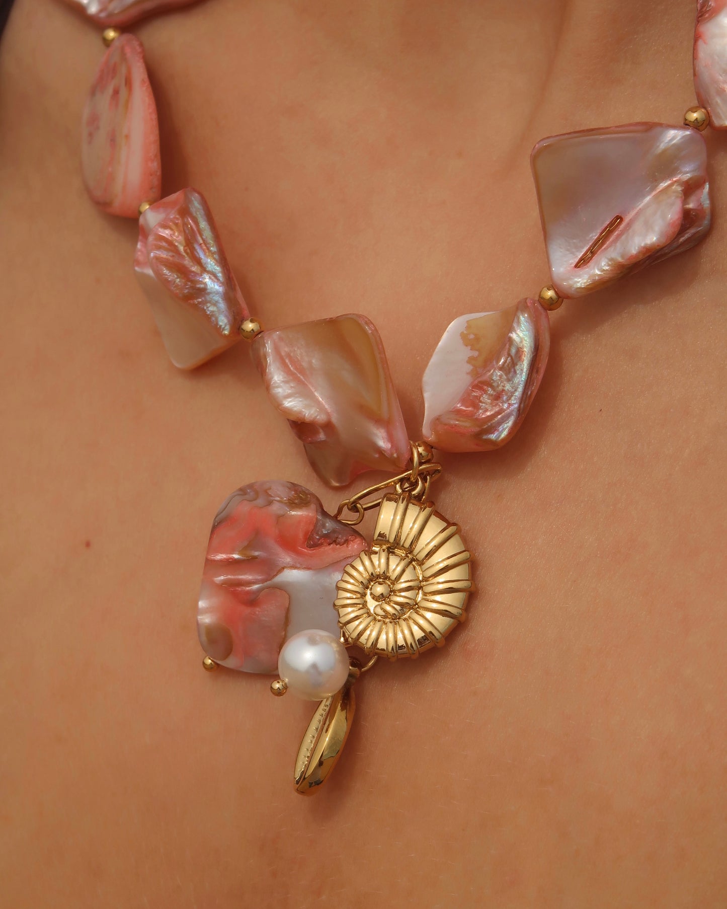 Statement ketting van roze schelpen met gouden hangers, waaronder schelpen