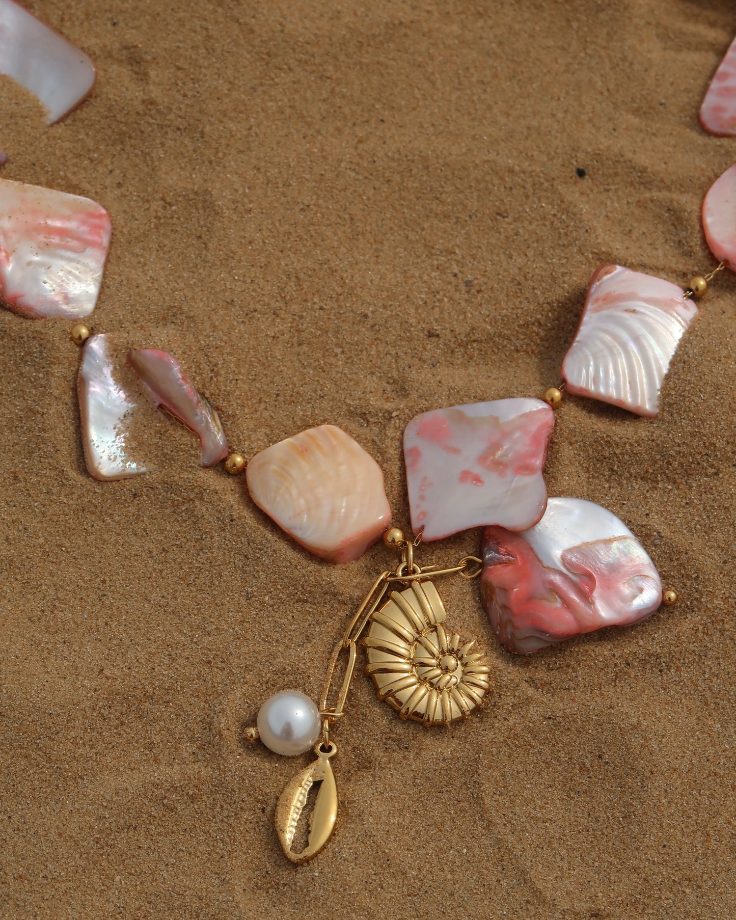 Statement ketting van roze schelpen met gouden hangers, waaronder schelpen