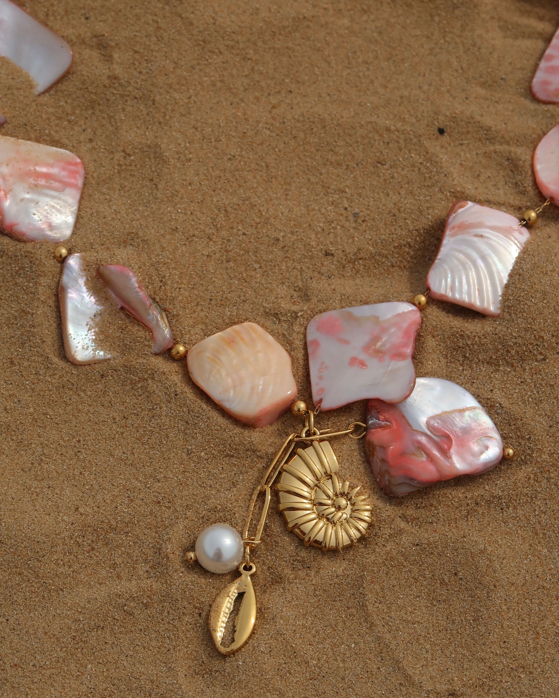 Statement ketting van roze schelpen met gouden hangers, waaronder schelpen