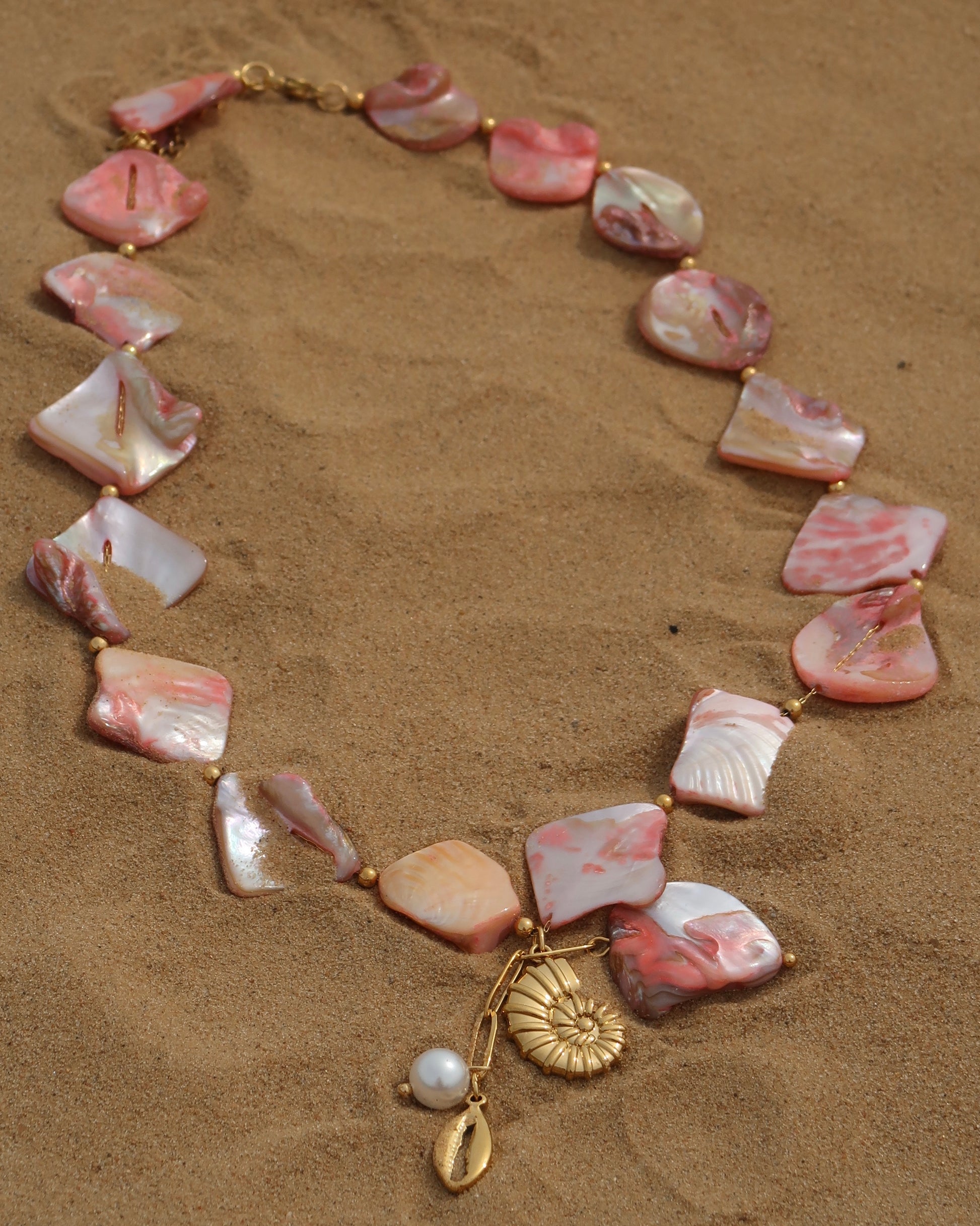 Statement ketting van roze schelpen met gouden hangers, waaronder schelpen