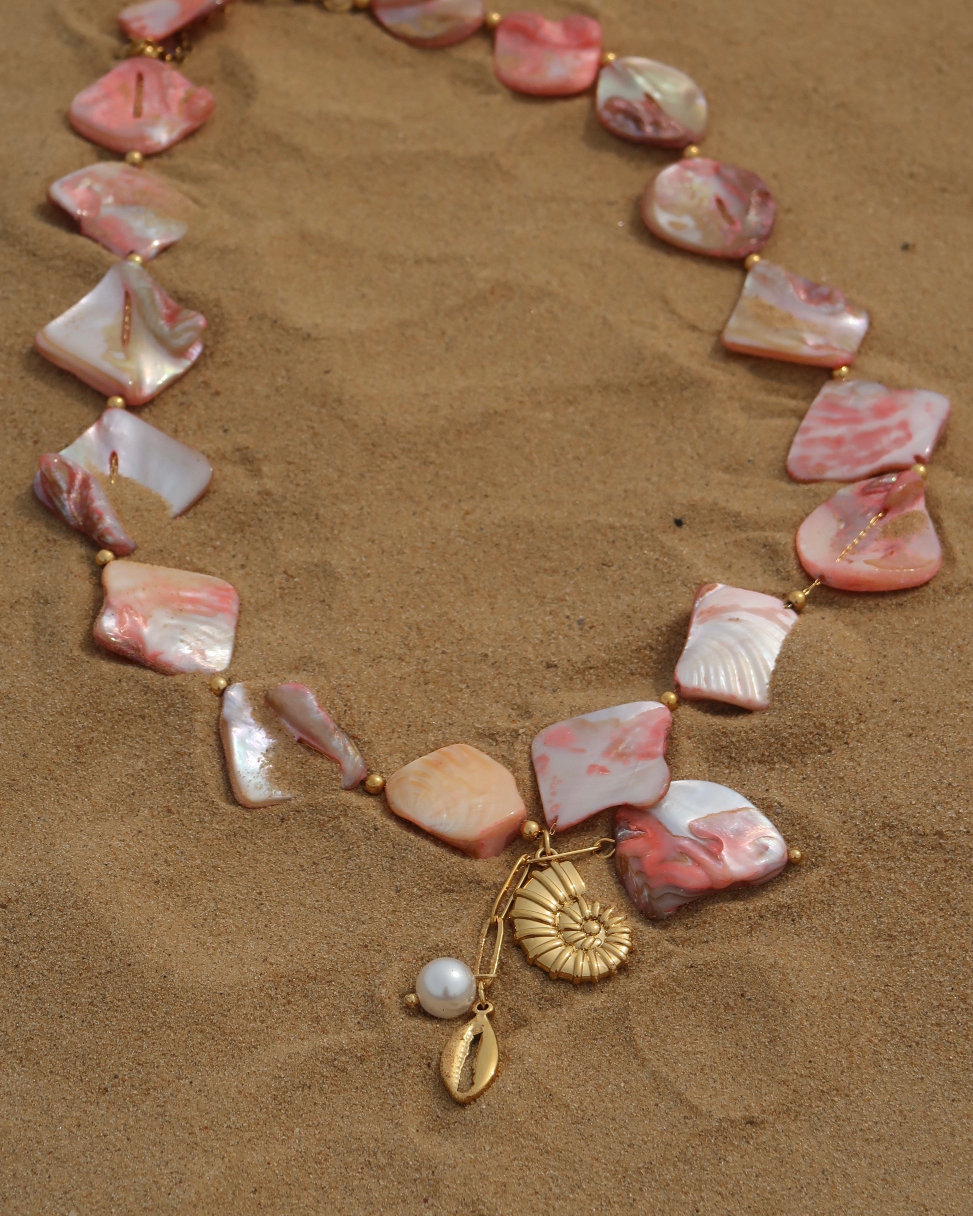 Statement ketting van roze schelpen met gouden hangers, waaronder schelpen