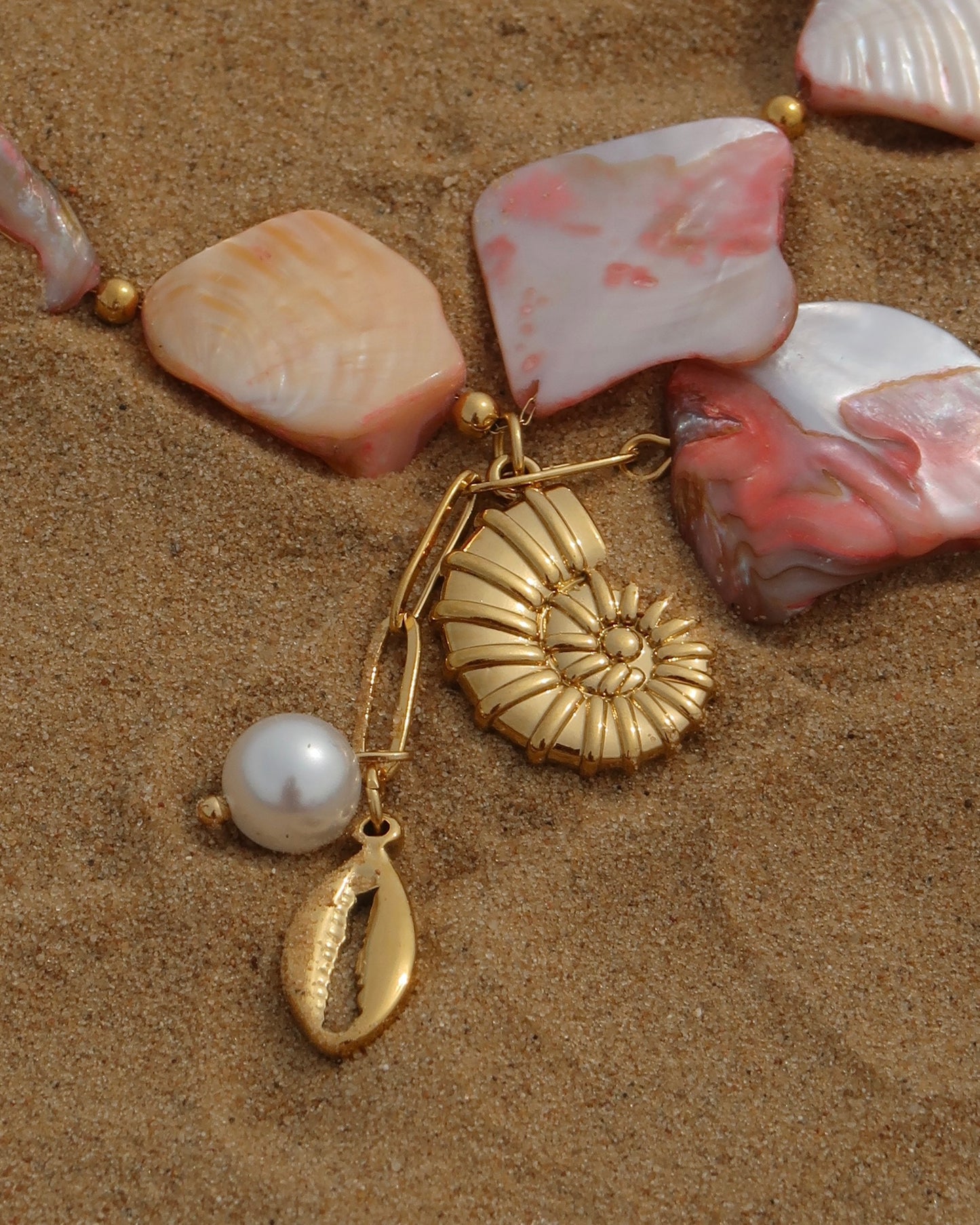 Statement ketting van roze schelpen met gouden hangers, waaronder schelpen