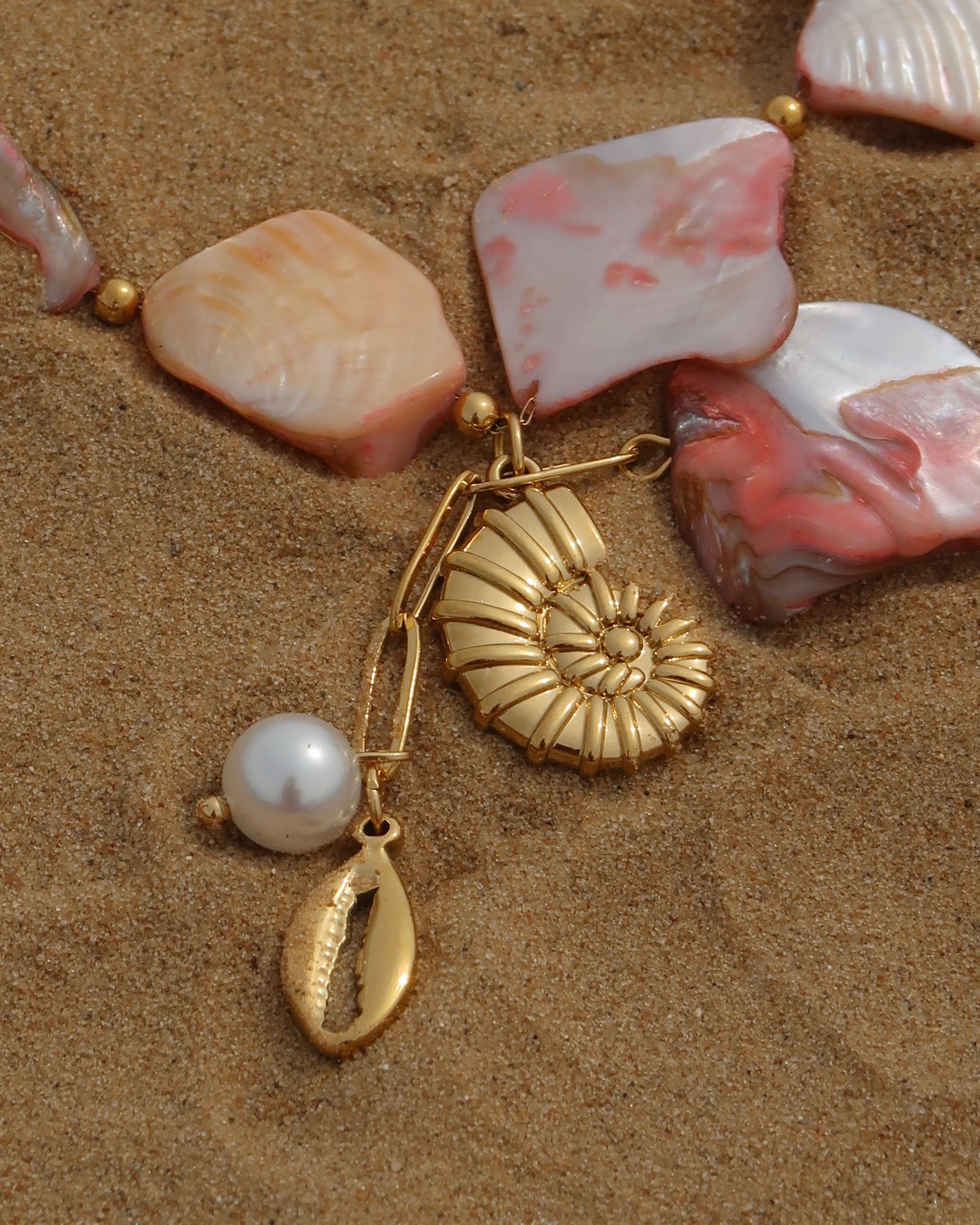 Statement ketting van roze schelpen met gouden hangers, waaronder schelpen