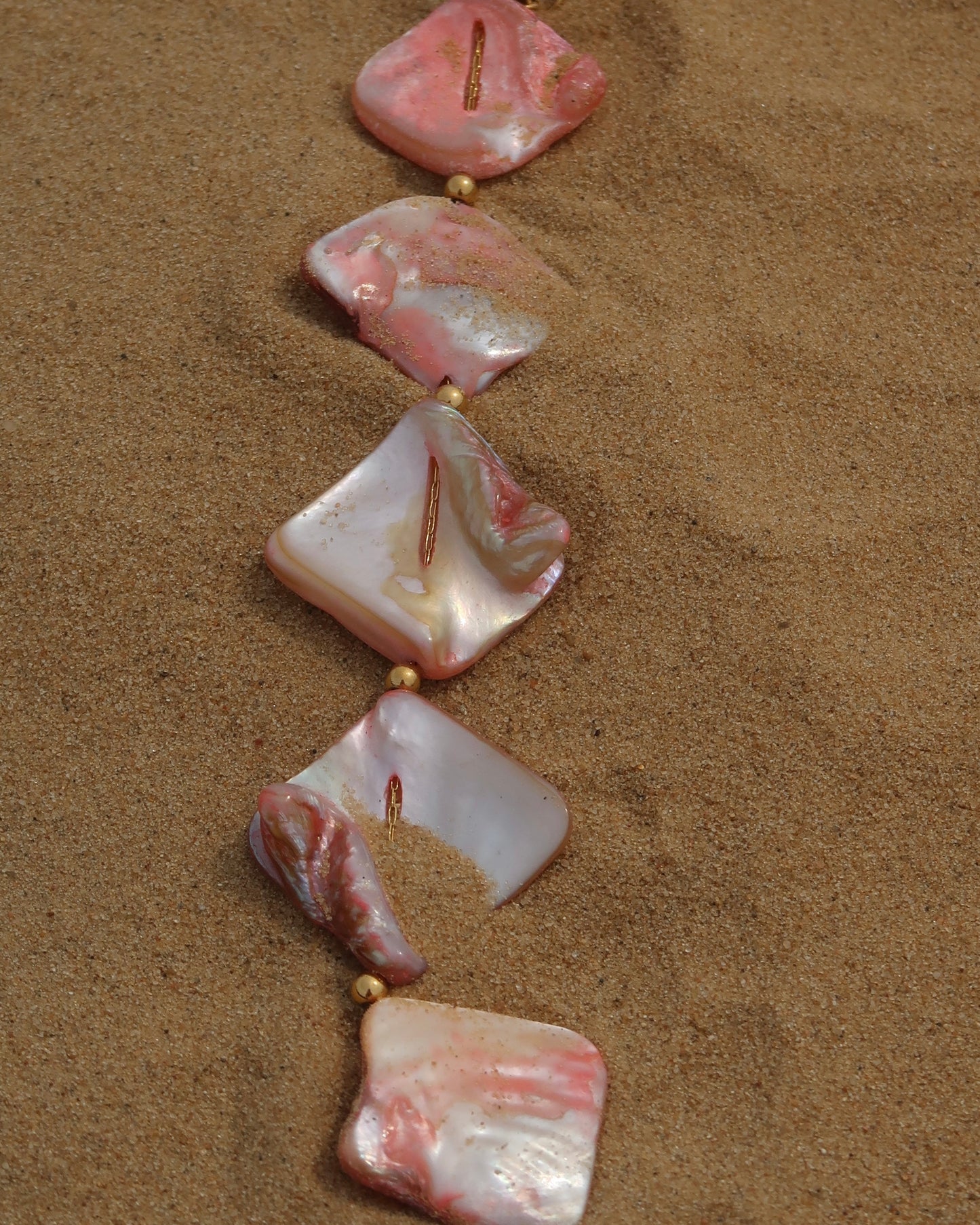 Statement ketting van roze schelpen met gouden hangers, waaronder schelpen