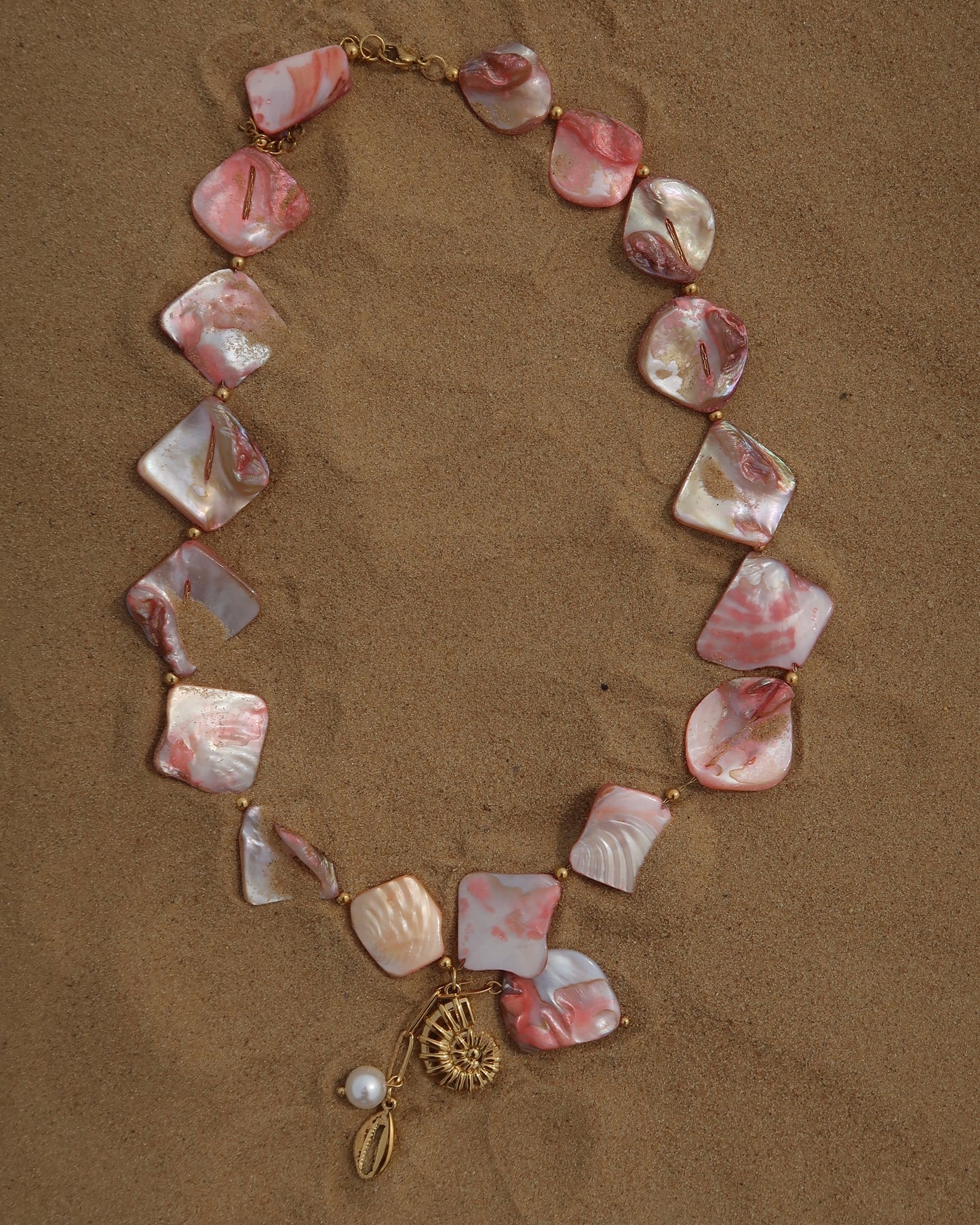 Statement ketting van roze schelpen met gouden hangers, waaronder schelpen
