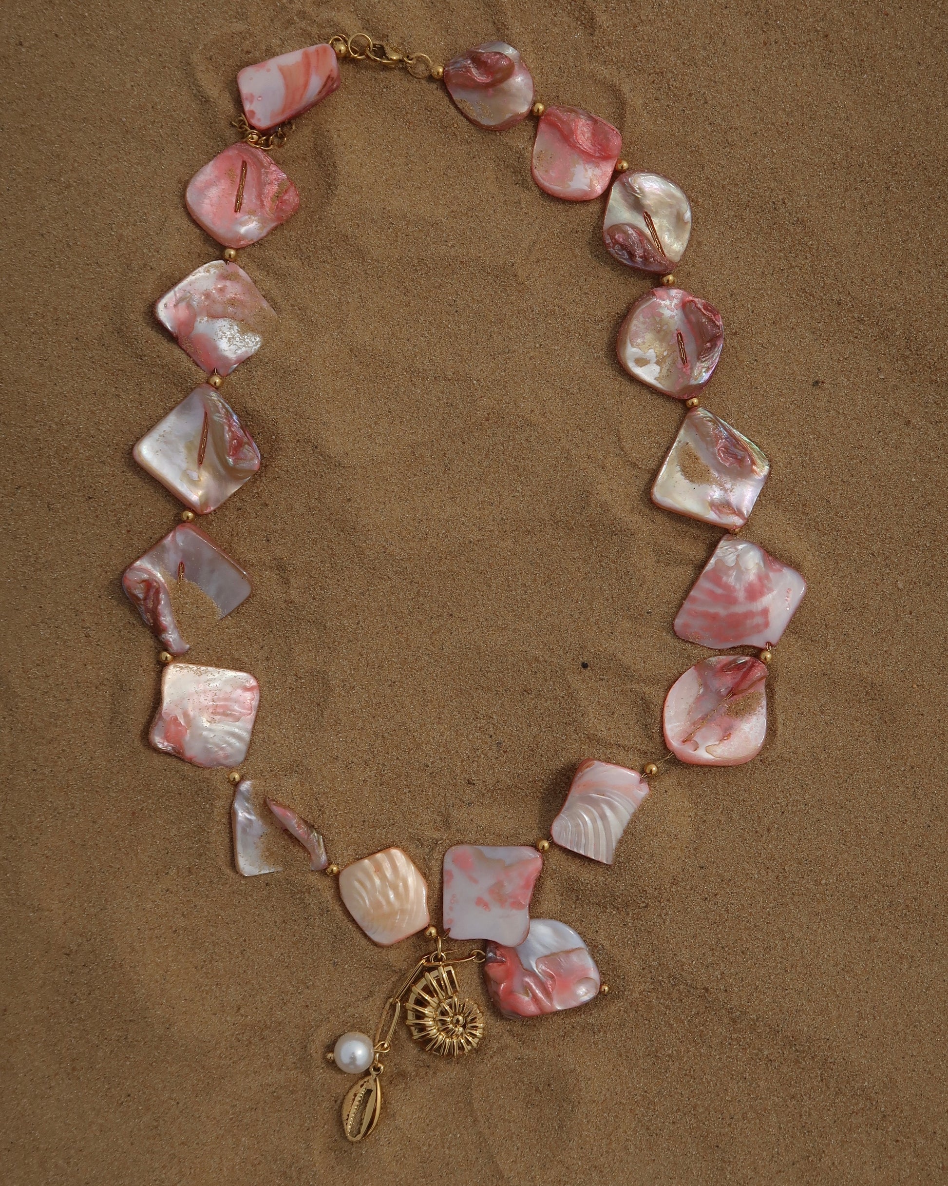 Statement ketting van roze schelpen met gouden hangers, waaronder schelpen